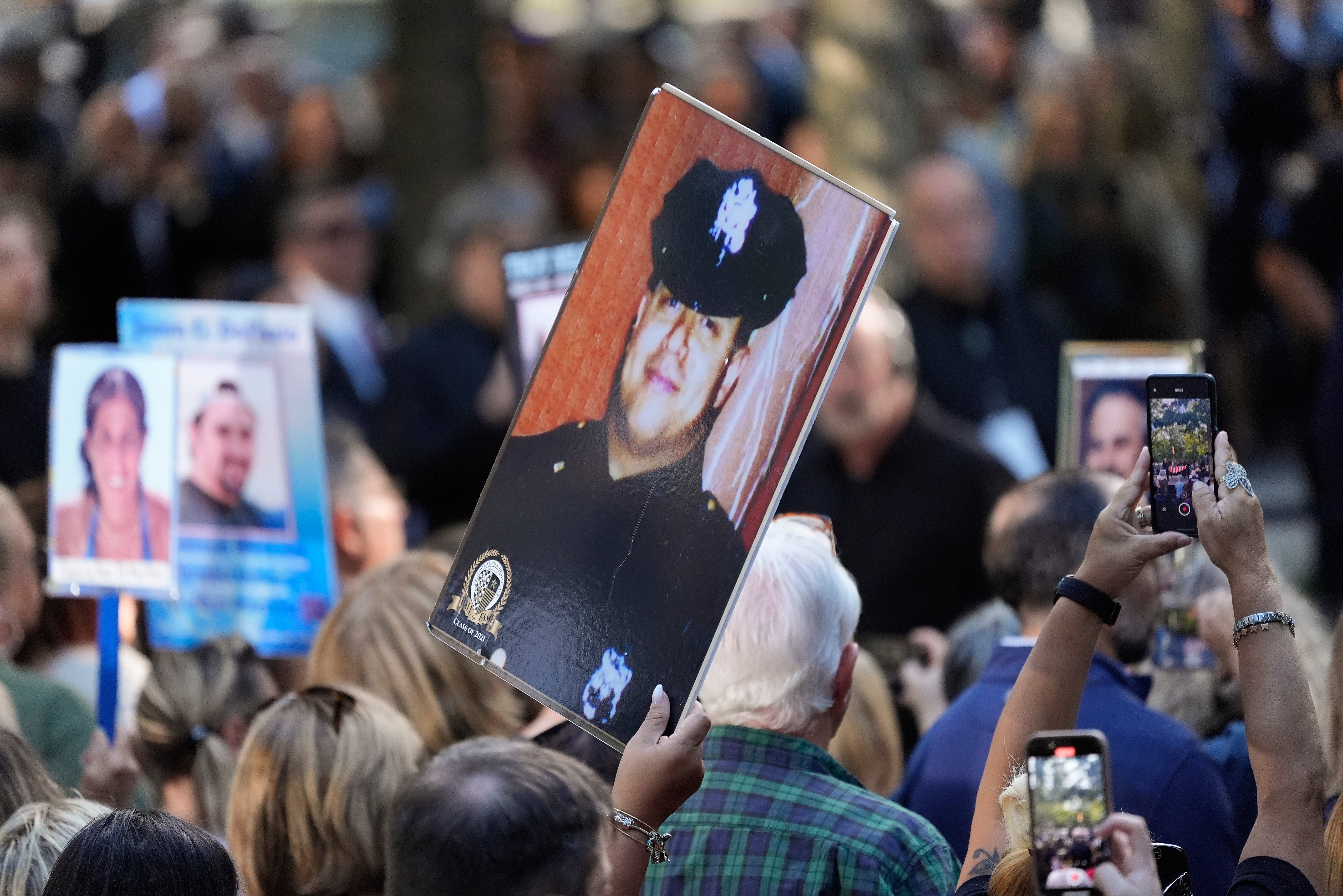 A woman holds up a photo of a New York City Police officer during the 9/11 Memorial ceremony on the 23rd anniversary of the September 11 attacks in New York