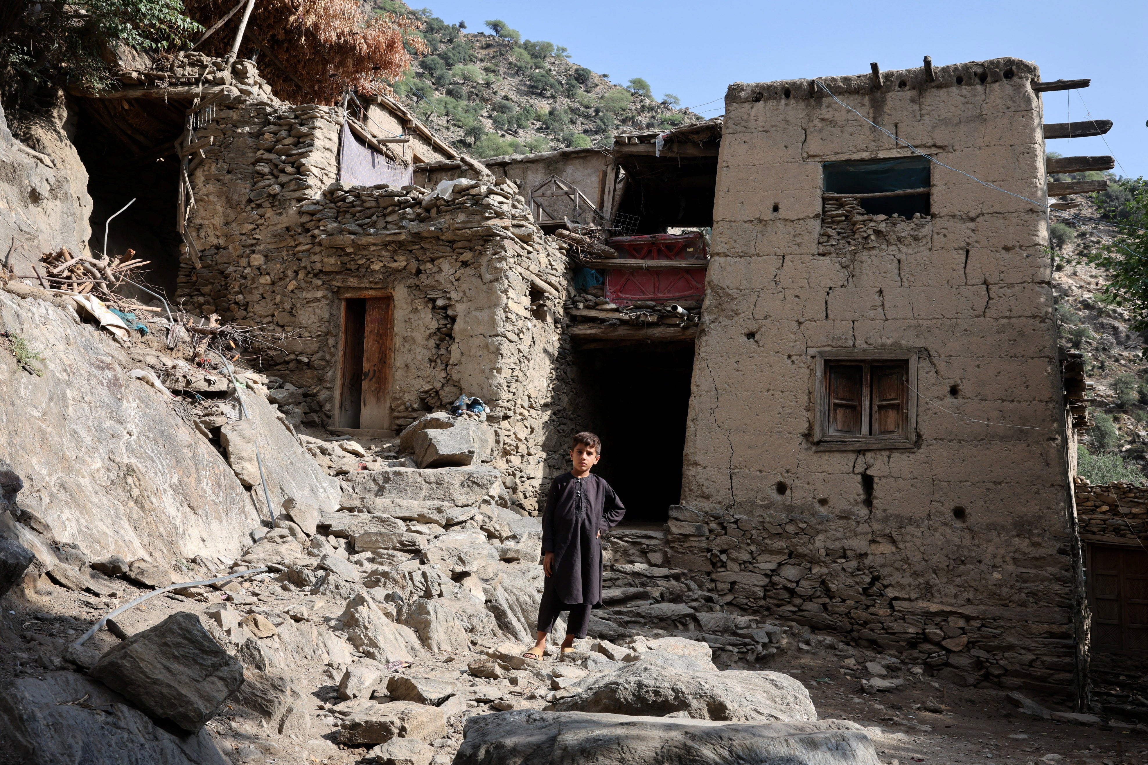 A boy stands in front of houses damaged by a deadly earthquake that struck Afghanistan's Kunar and Nangarhar provinces, at Masud village in Nurgal district, Kunar province