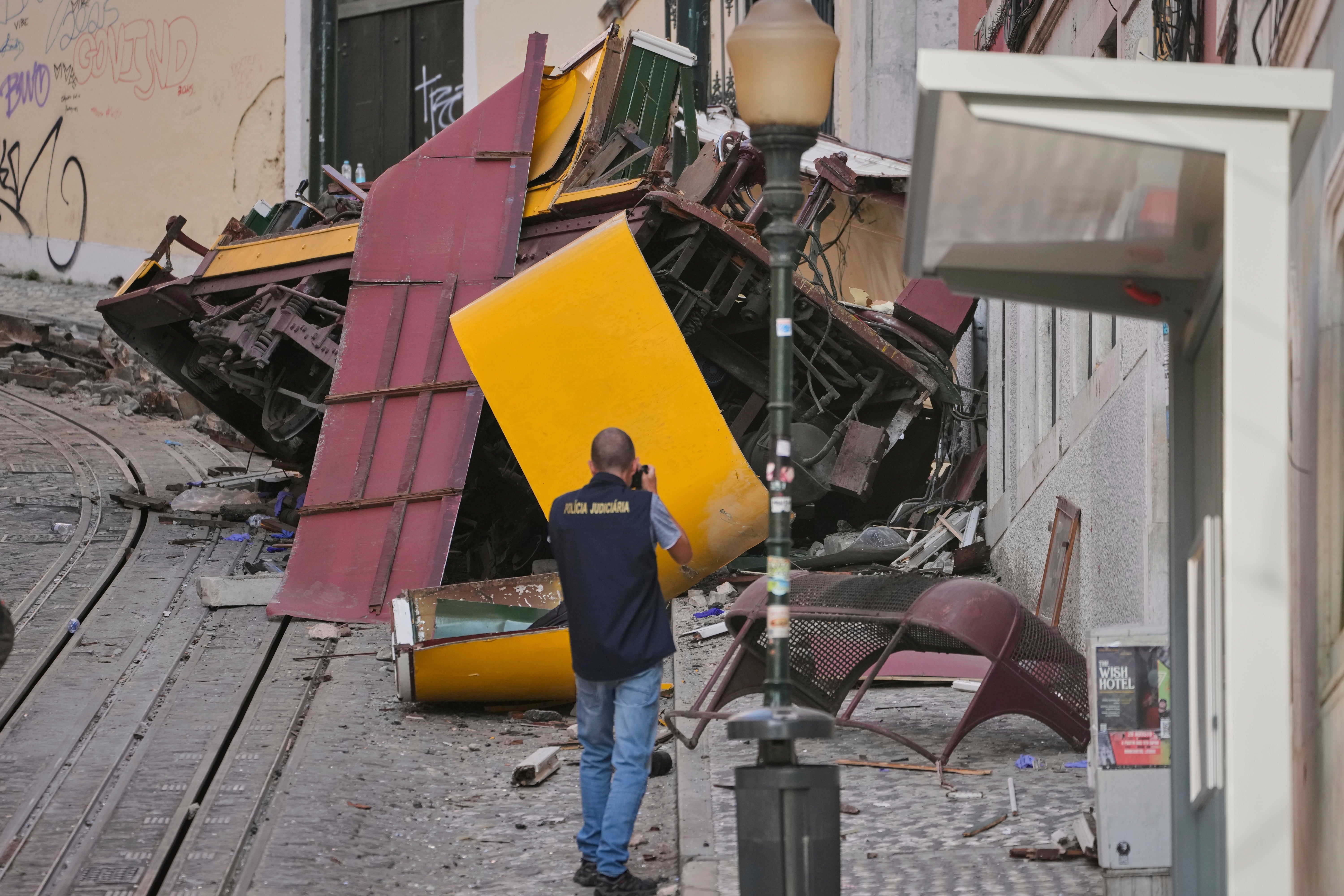 Police officers inspect the site where the tourist streetcar derailed and crashed in Lisbon