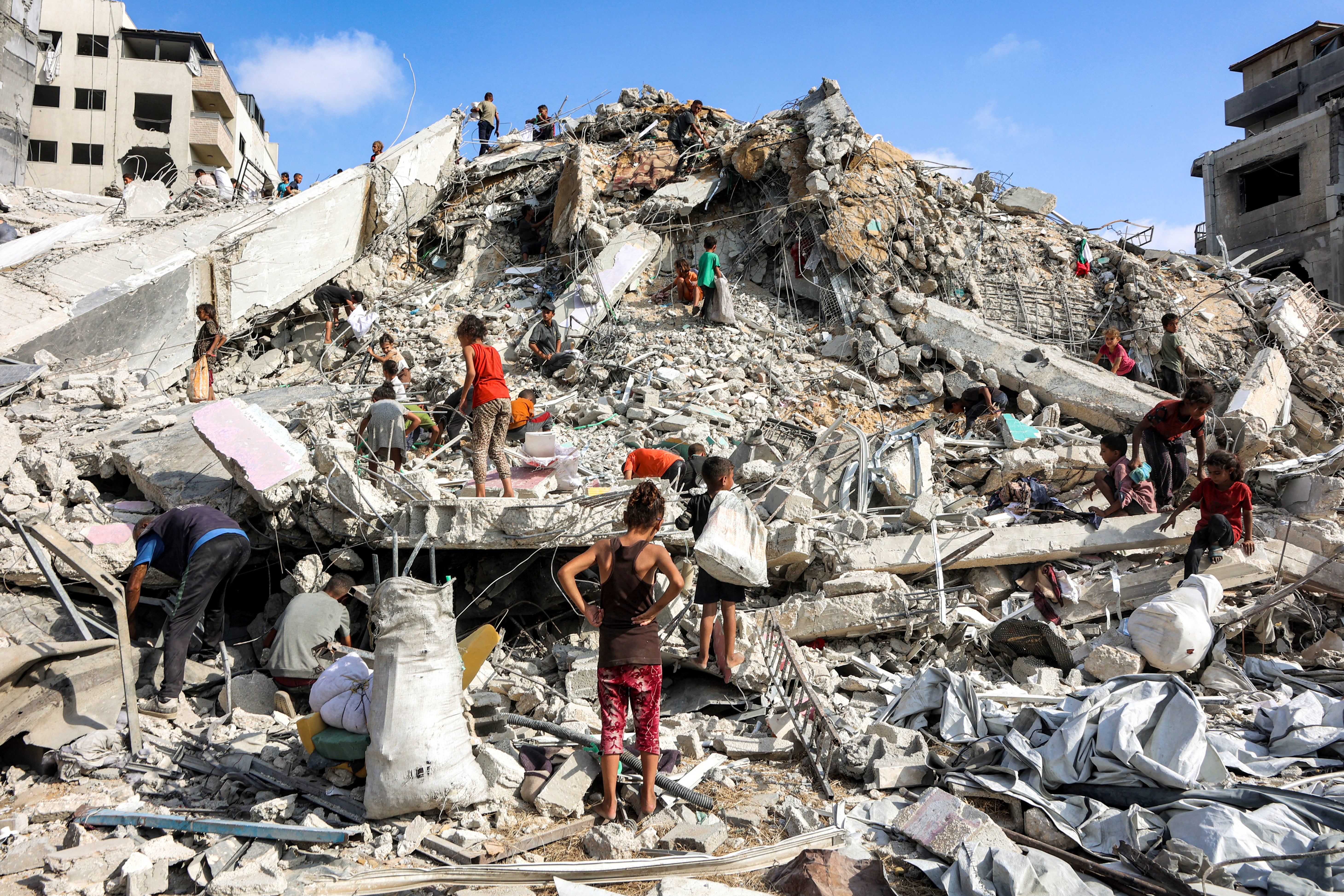 People search the mound of rubble at the site of the destroyed Sussi Tower in Gaza City