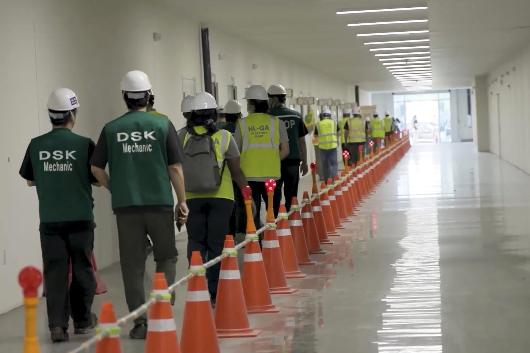 This image from video provided by U.S. Immigration and Customs Enforcement via DVIDS shows manufacturing plant employees being escorted outside the Hyundai Motor Group’s electric vehicle plant