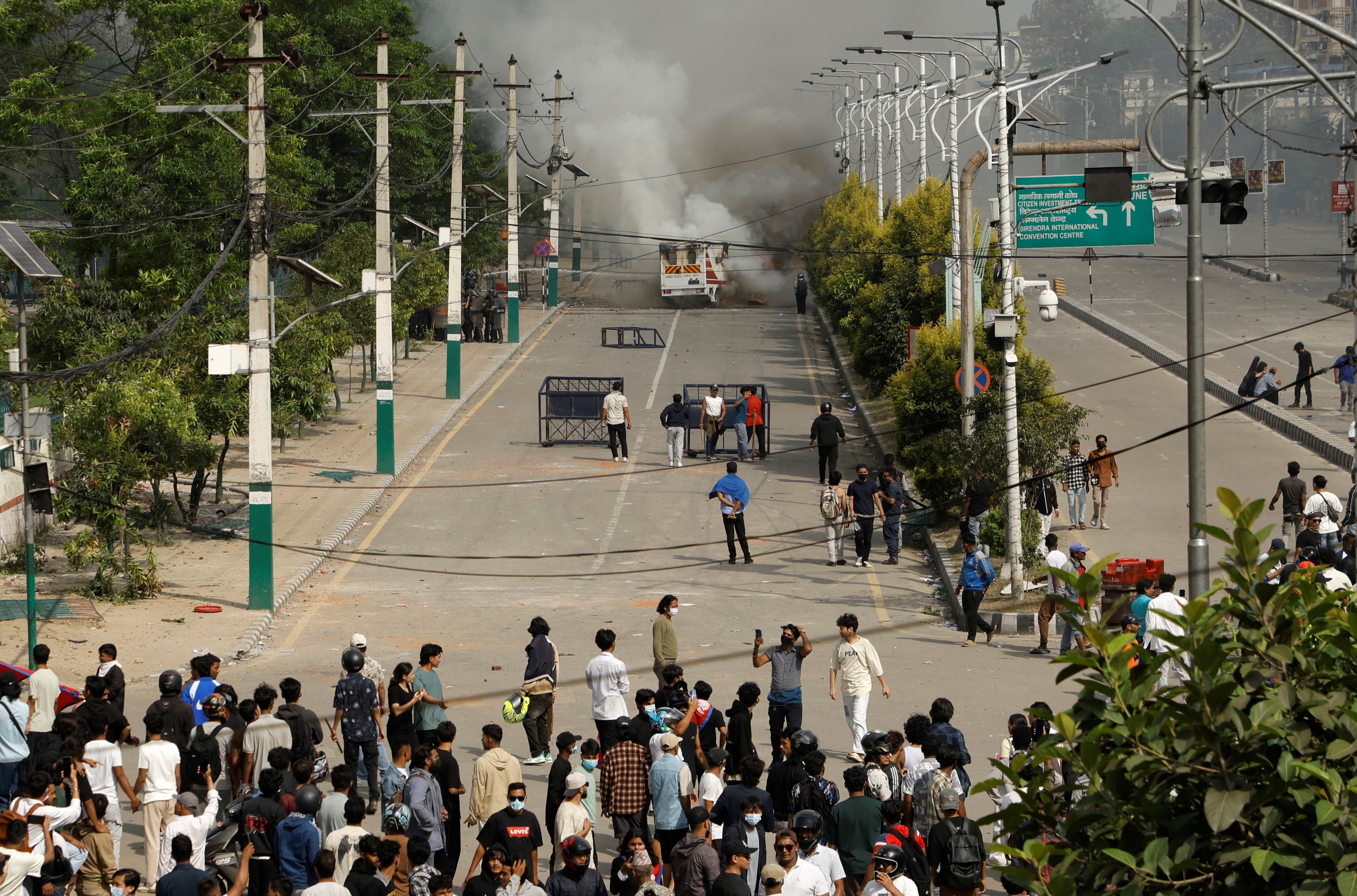 Smoke billows from an ambulance next to riot police officers and demonstrators during a protest against corruption and the government's decision to block several social media platforms, in Kathmandu, Nepal