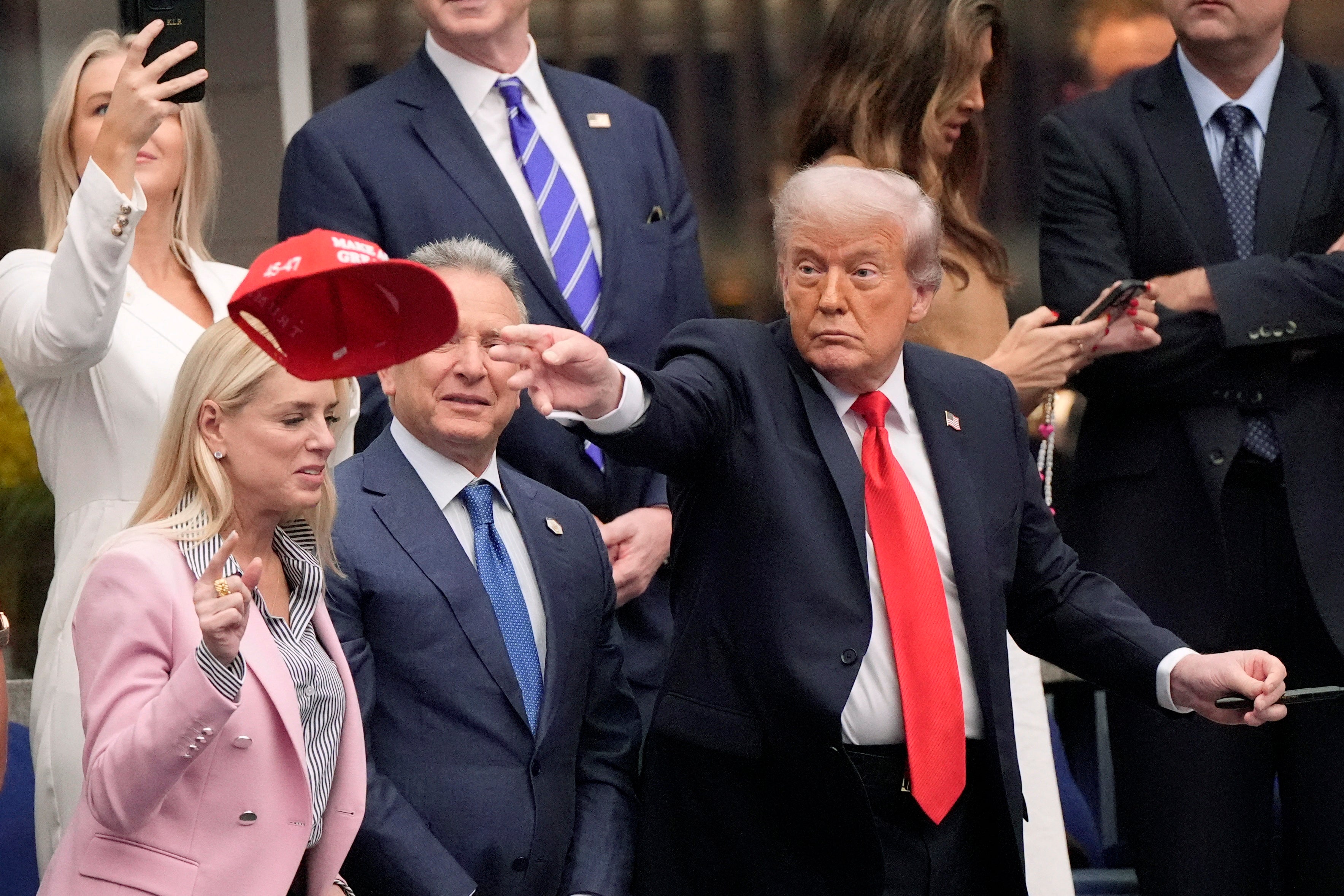 Trump's Press Secretary Karoline Leavitt (top left) recorded the president signing several caps inside the Arthur Ashe Stadium