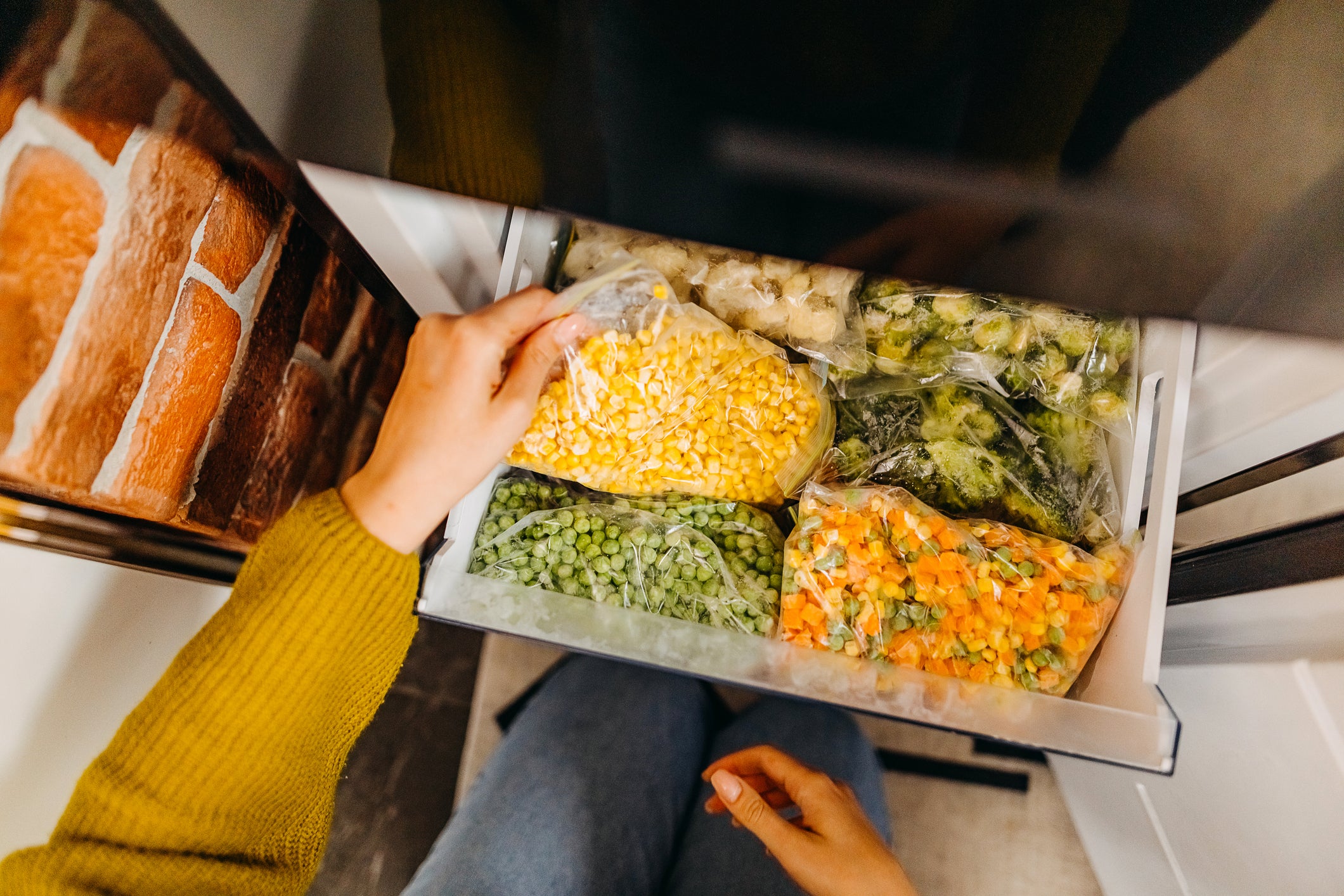 A woman grabs a package of frozen corn from the freezer. All corn has sugar, but it’s also a good source of fiber that can regulate blood sugar