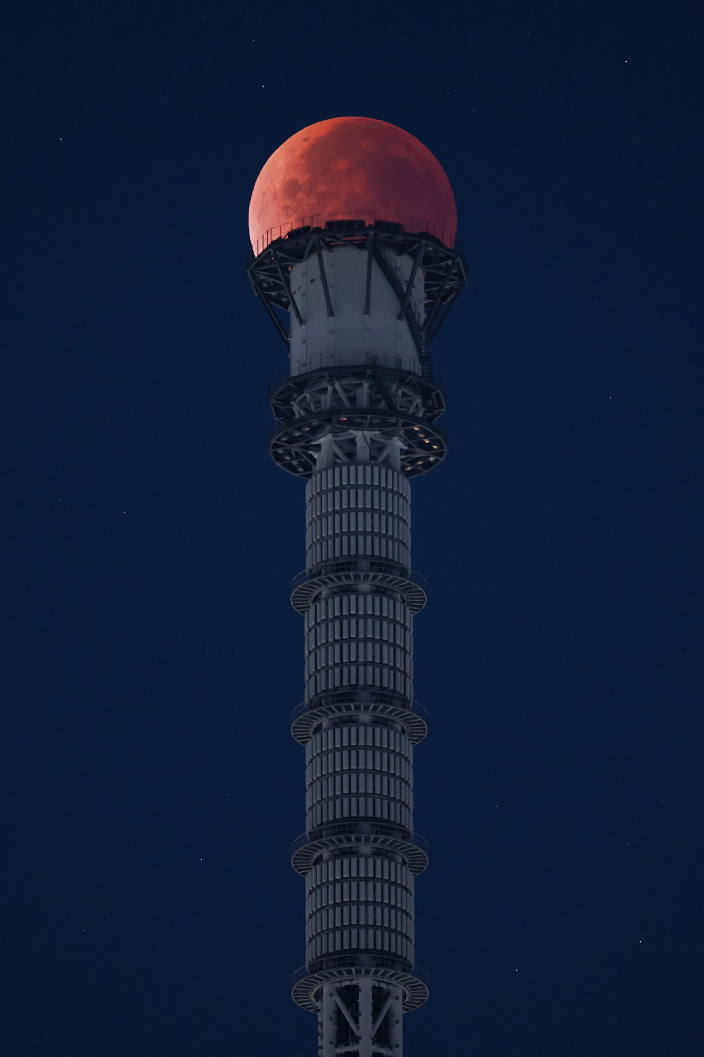 The moon appears at the very top of the Tokyo Skytree during a total lunar eclipse in the middle of the night above the Japanese capital early on 8 September 2025