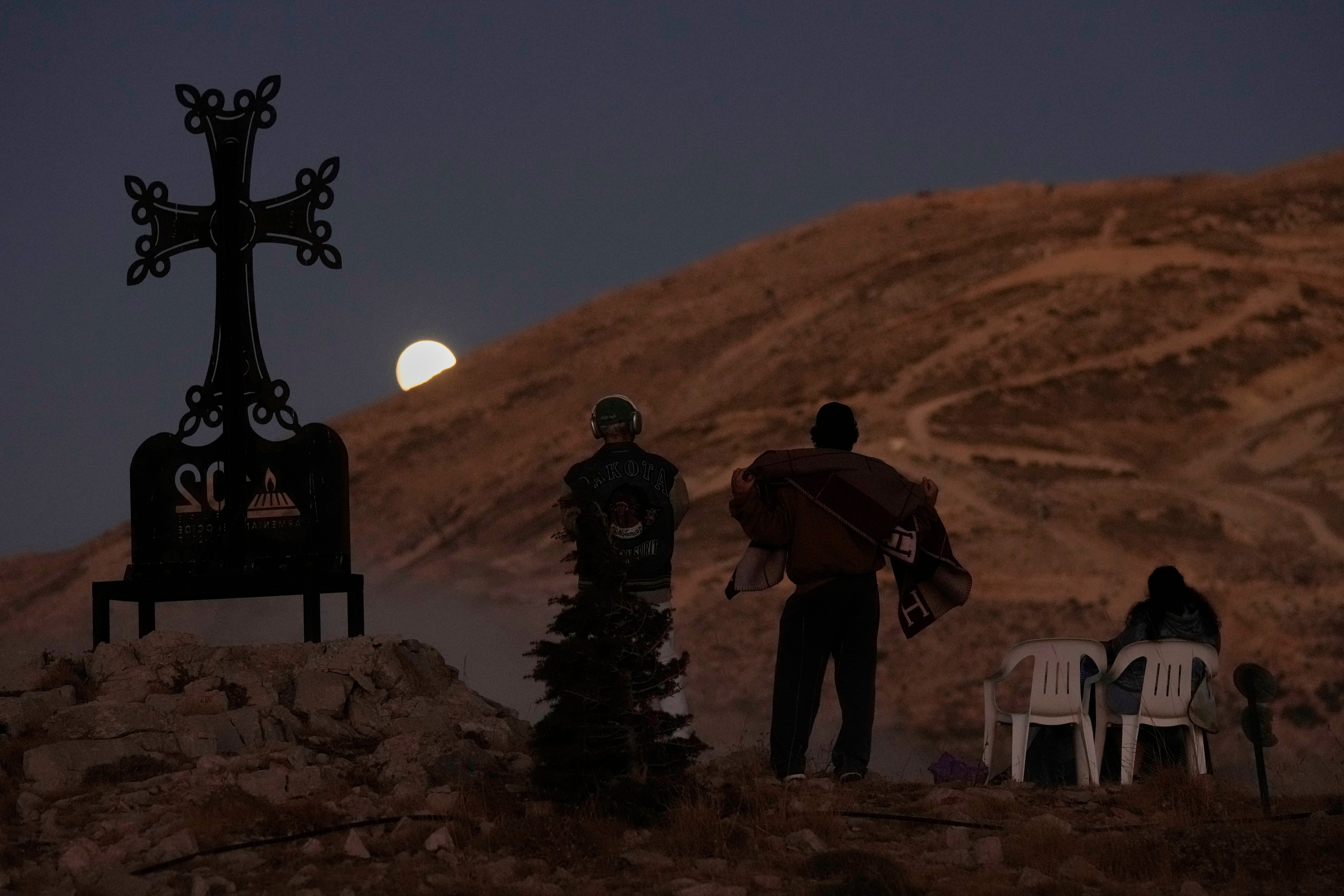 People watch as the moon shines during a total lunar eclipse over Kfardebian village, northeast of Beirut, Lebanon, Sunday, 7 September 2025