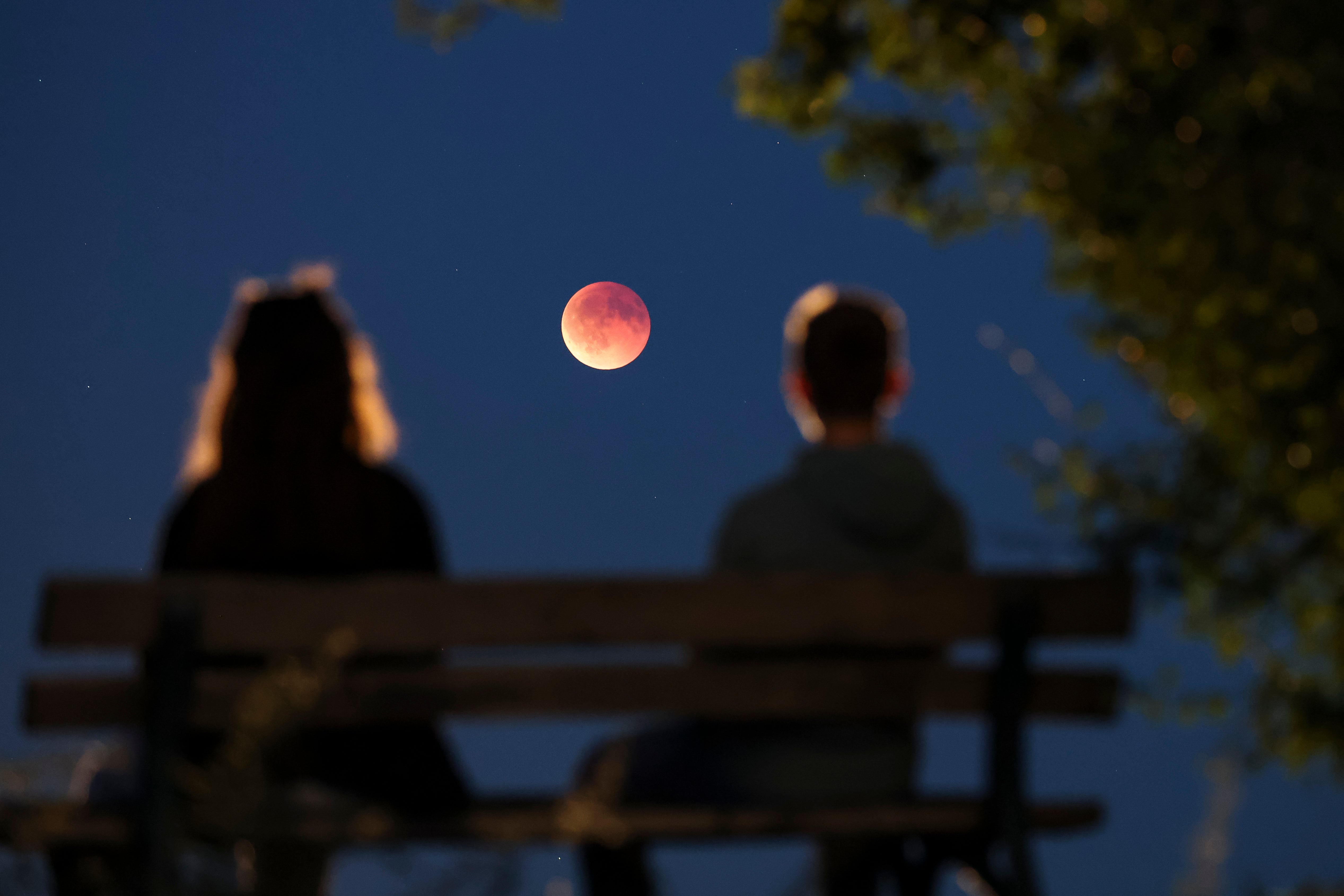 Onlookers watch the total lunar eclipse, also known as the blood moon, from a park bench, in Leipzig, Germany, Sunday, 7 September 2025