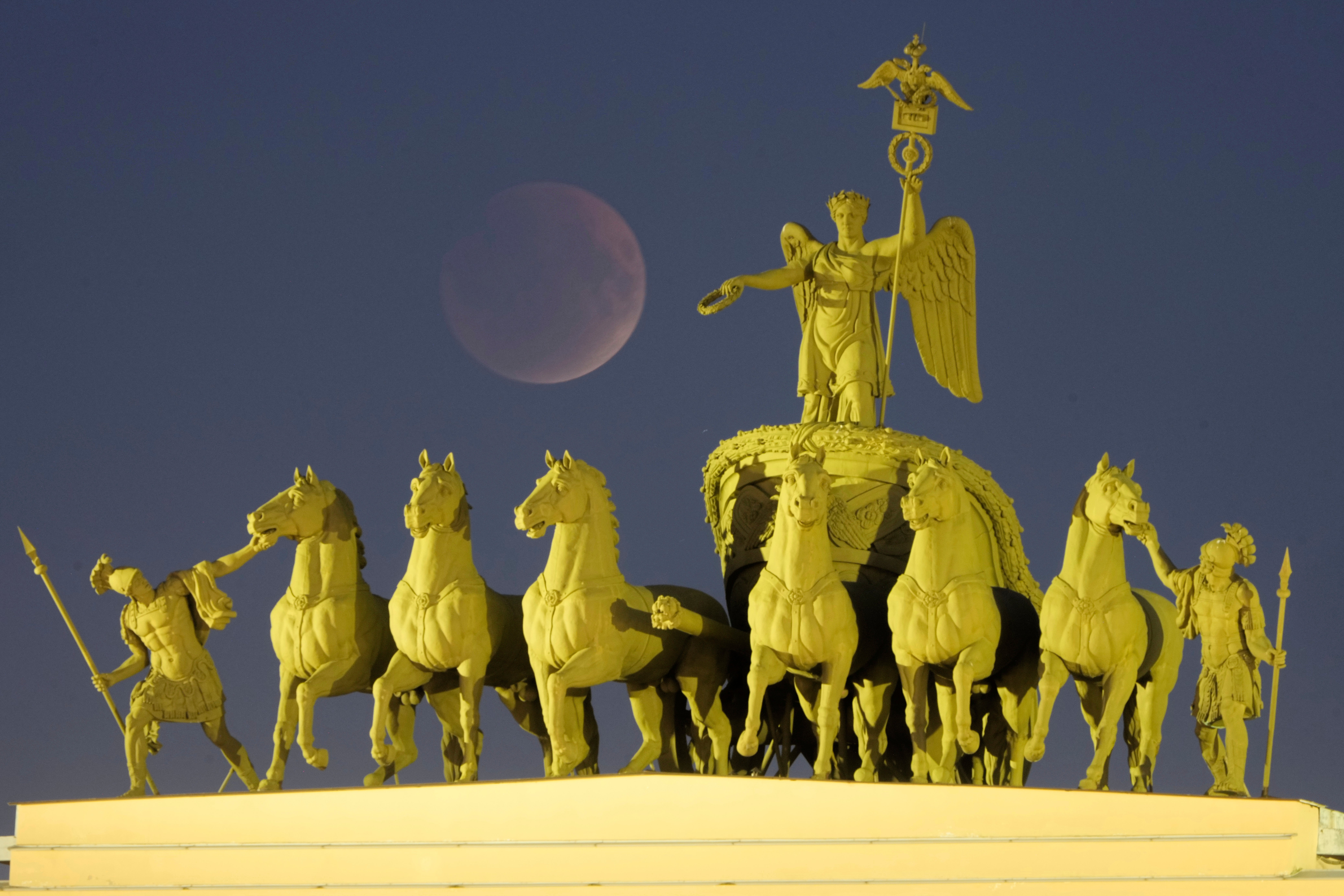 The full moon rises behind a sculpture of a chariot at the Palace Square for a total lunar eclipse in St Petersburg, Russia, Sunday, 7 September 2025