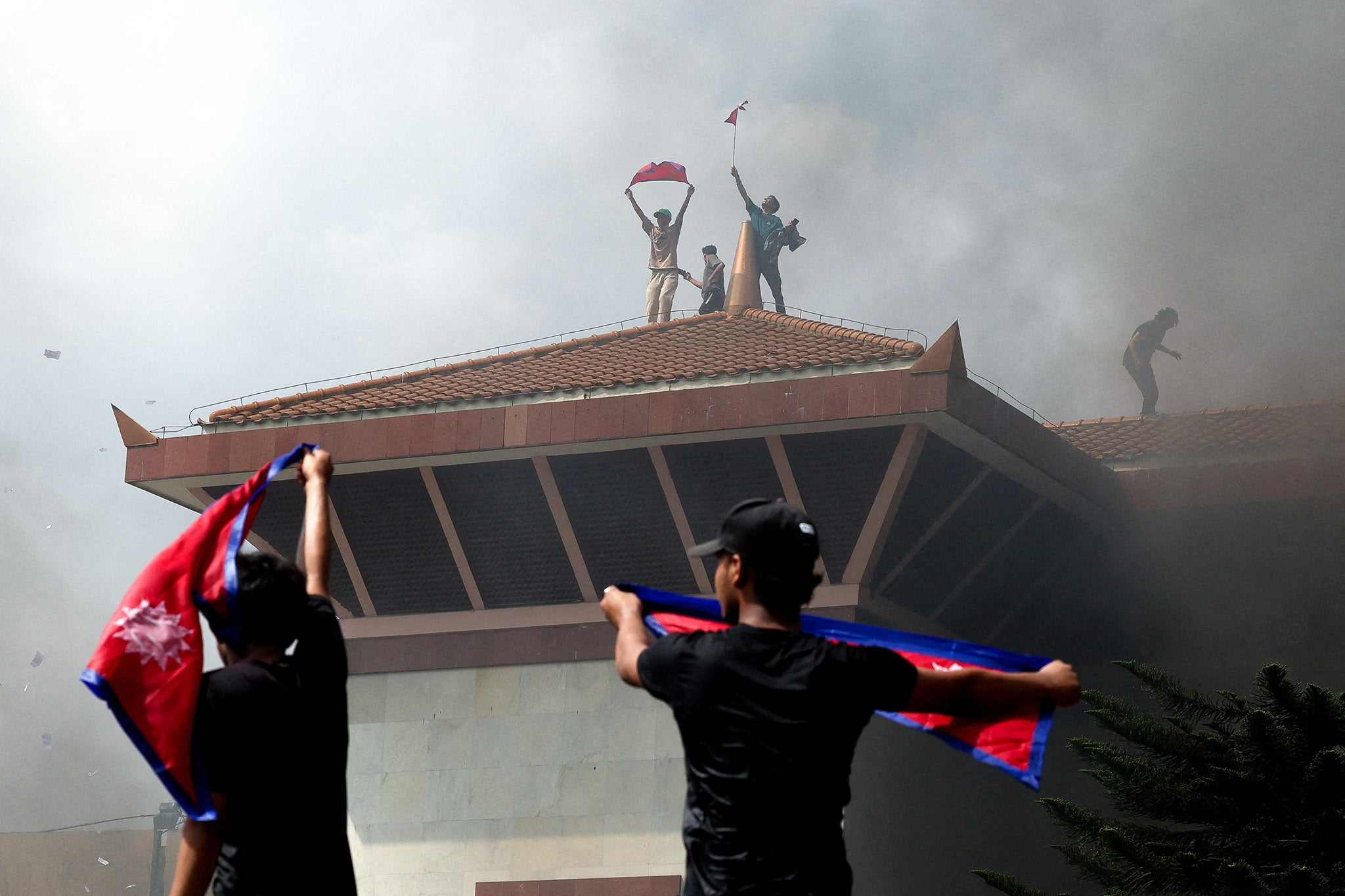 Protesters wave flags on the roof of the parliament complex