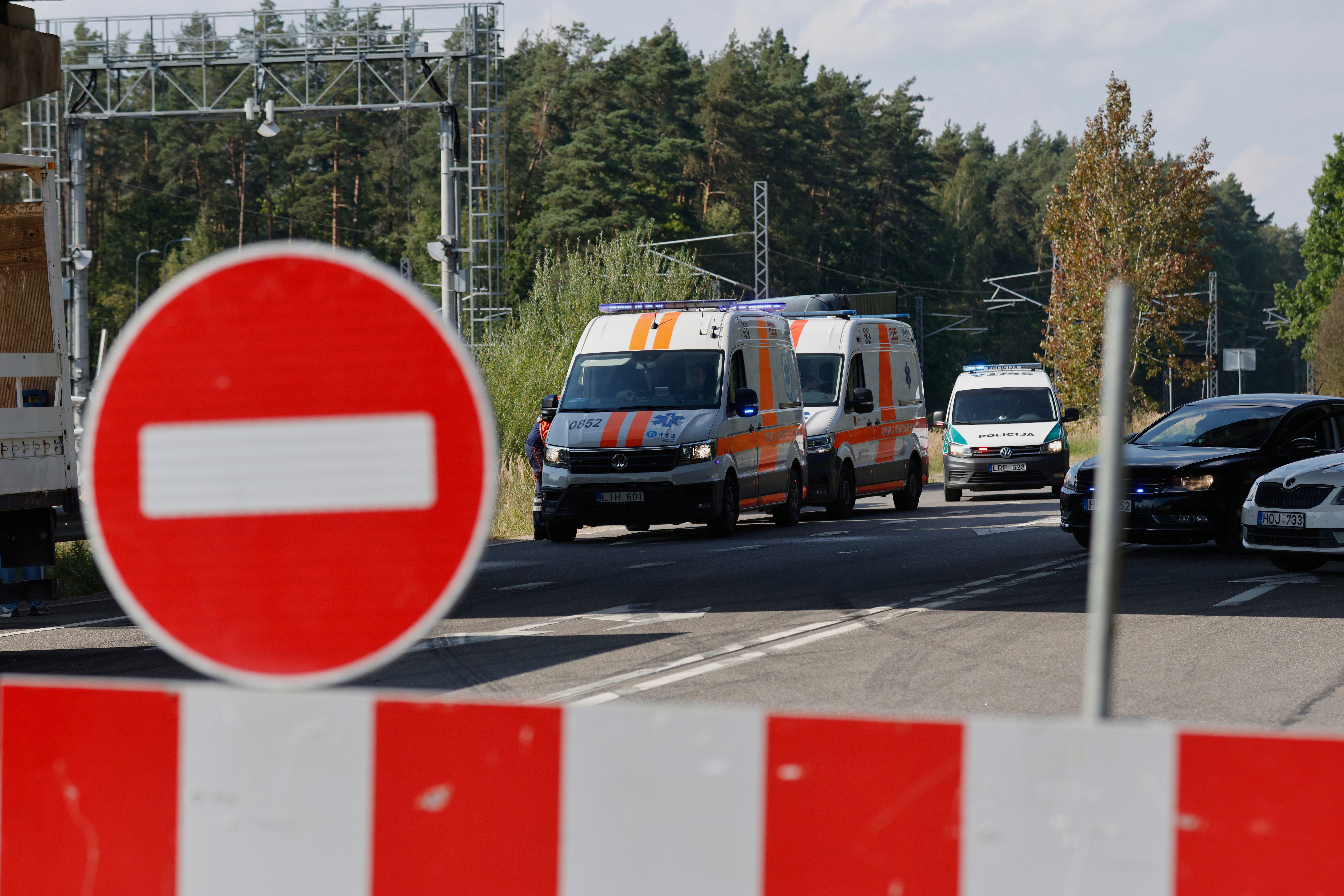 Ambulances and police cars are parked on the road not far from the area of powerful explosions after several rail cars loaded with liquefied gas caught fire in the suburbs of Vilnius, Lithuania, Wednesday, Sept. 10, 2025. (AP Photo/Mindaugas Kulbis)