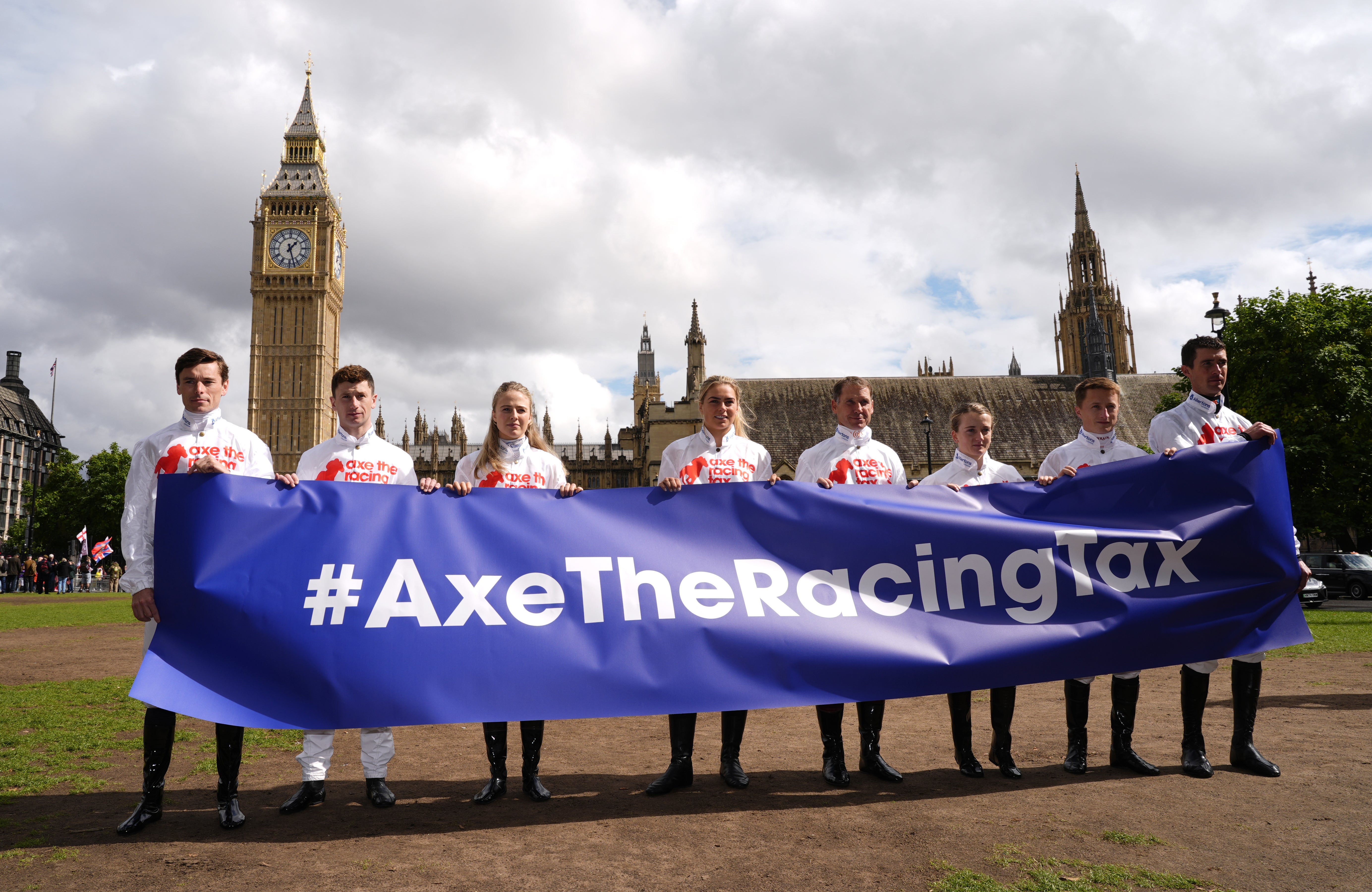 Kieran Shoemark, Oisin Murphy, Saffie Osborne, Lily Pinchin, Richard Johnson, Hollie Doyle, Tom Marquand and Paul O’Brien hold up an ‘Axe The Racing Tax’ banner in Parliament Square (Jordan Pettitt/PA)