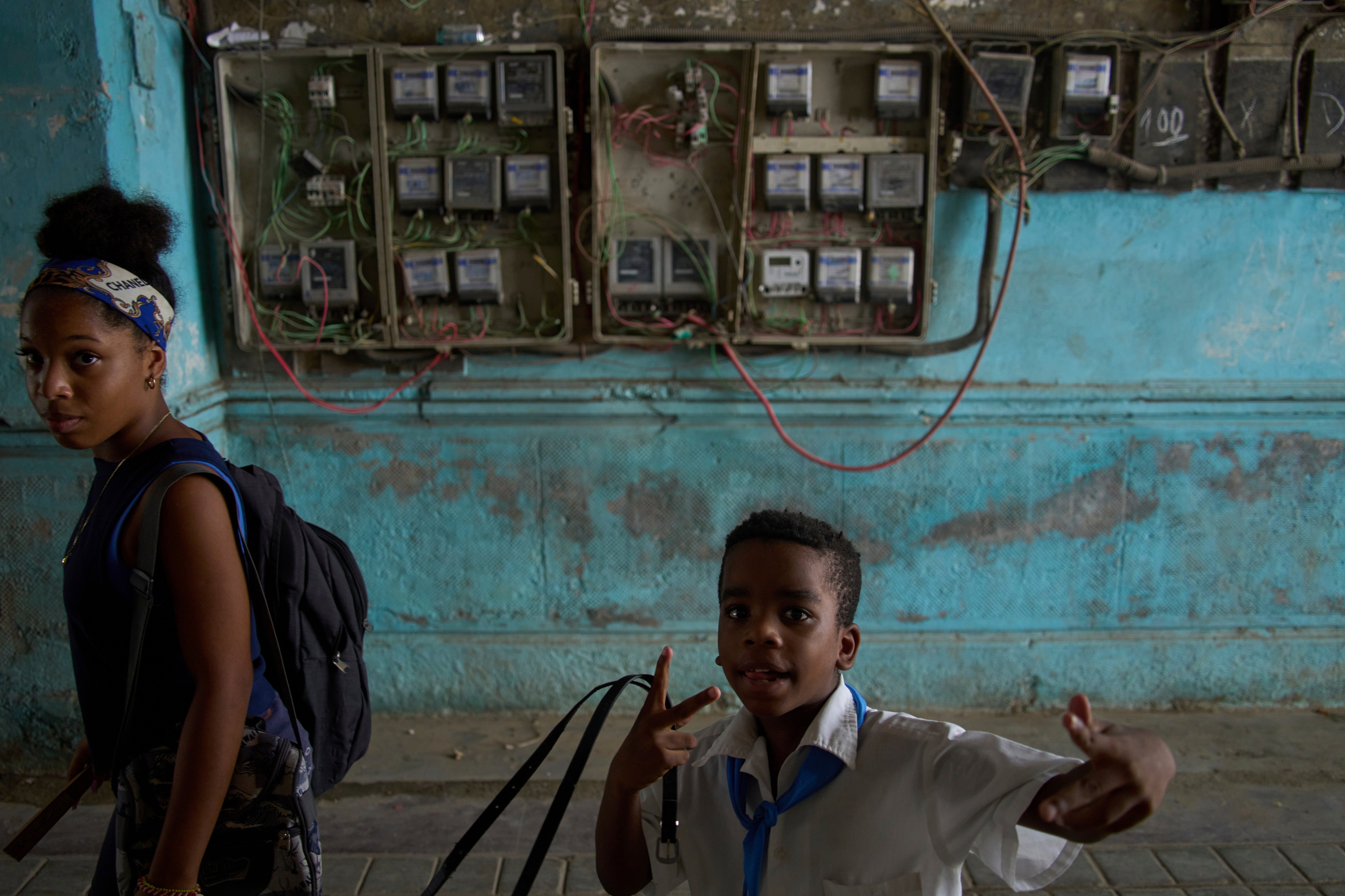 A youth stops to strike a pose in an apartment building where the electricity meters cover the wall during a blackout in Havana