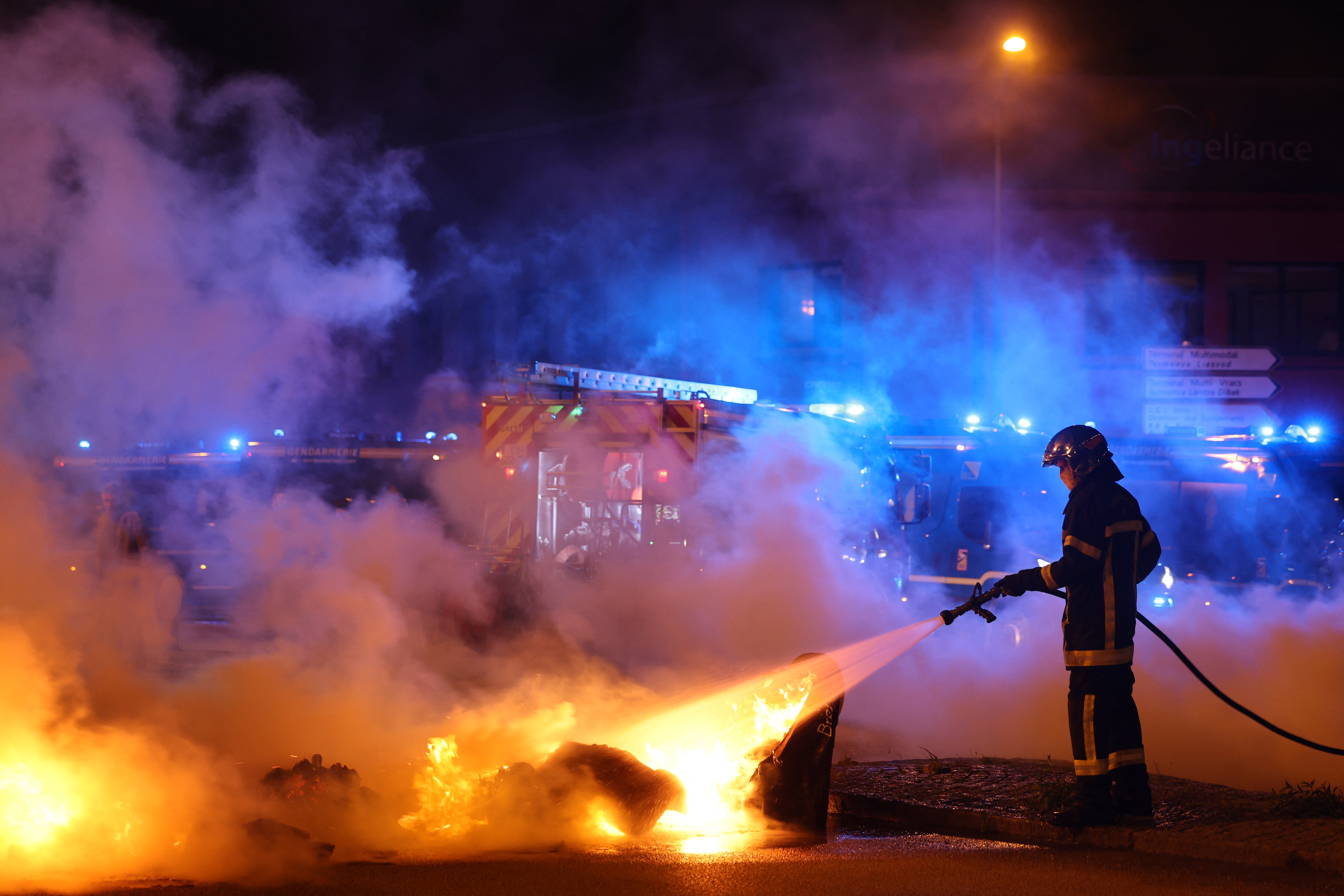 A firefighters extinguishes a fire at a roundabout, lit by protesters to block the access to the port of Brest
