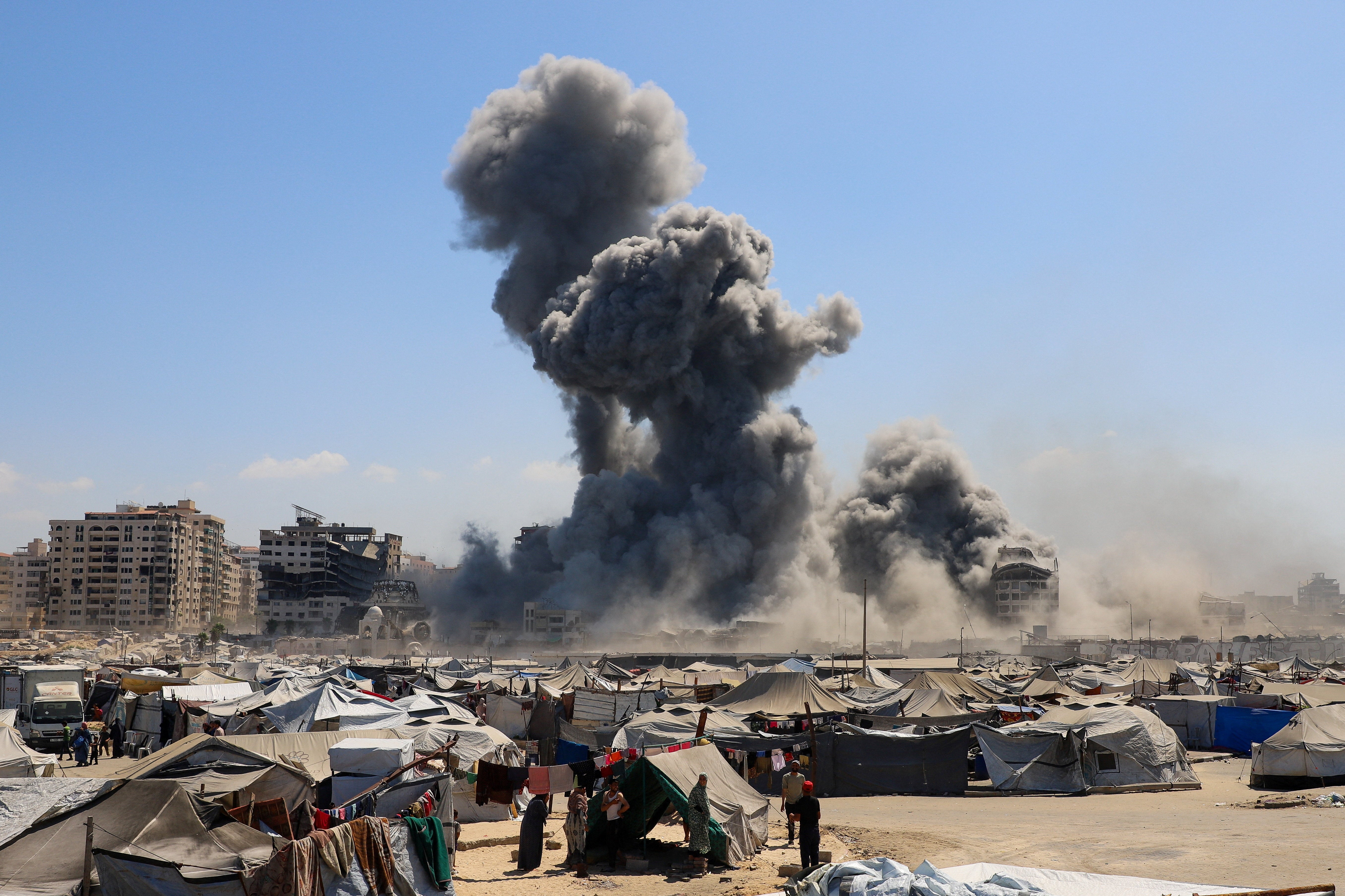 Smoke rises as an evacuated residential building, which was housing displaced Palestinians, collapses after it was hit by an Israeli airstrike in Gaza City