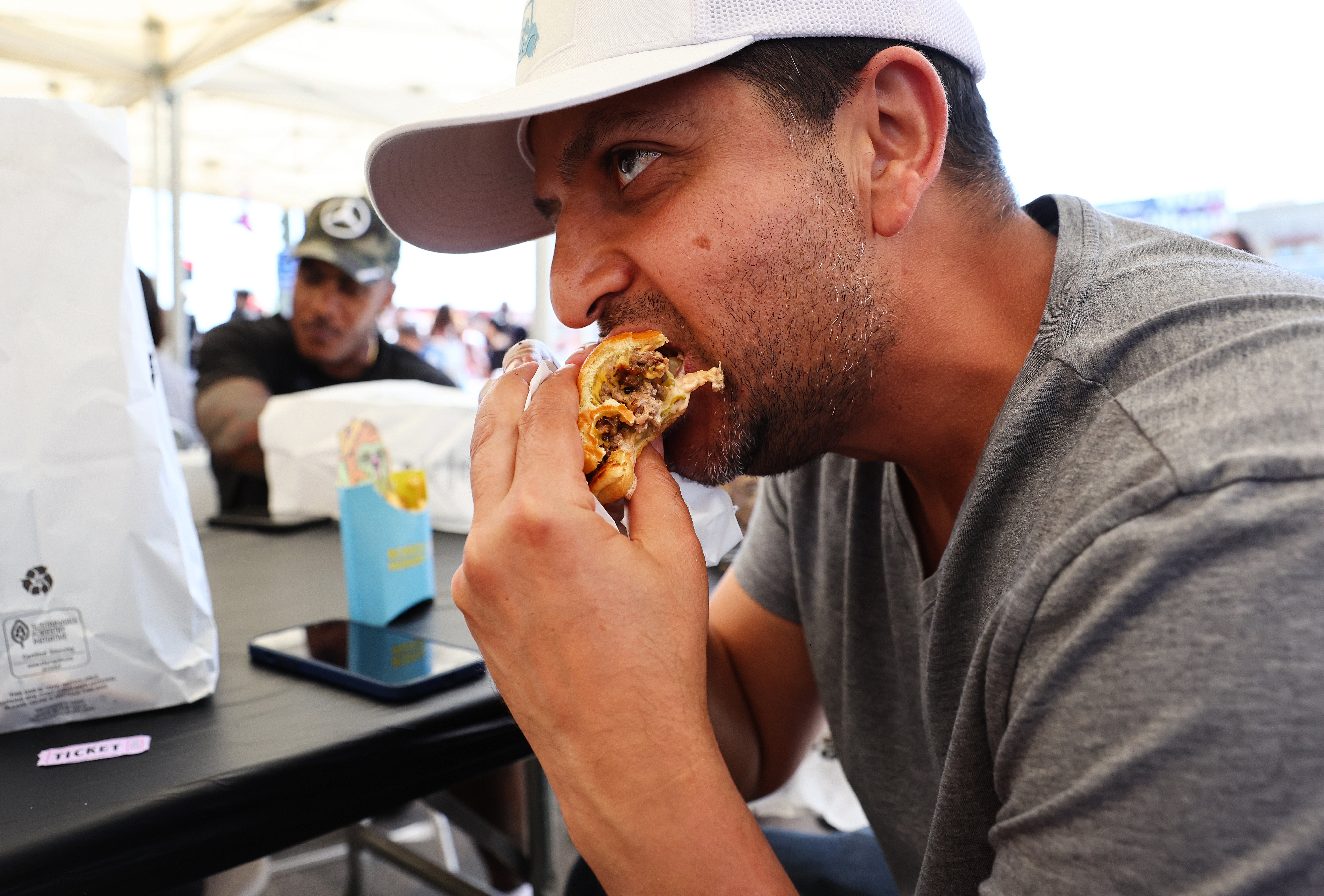 A customer eats a burger at the grand opening of the Bored & Hungry pop-up burger restaurant, which uses NFT art for its branding, on April 9, 2022 in Long Beach, California.