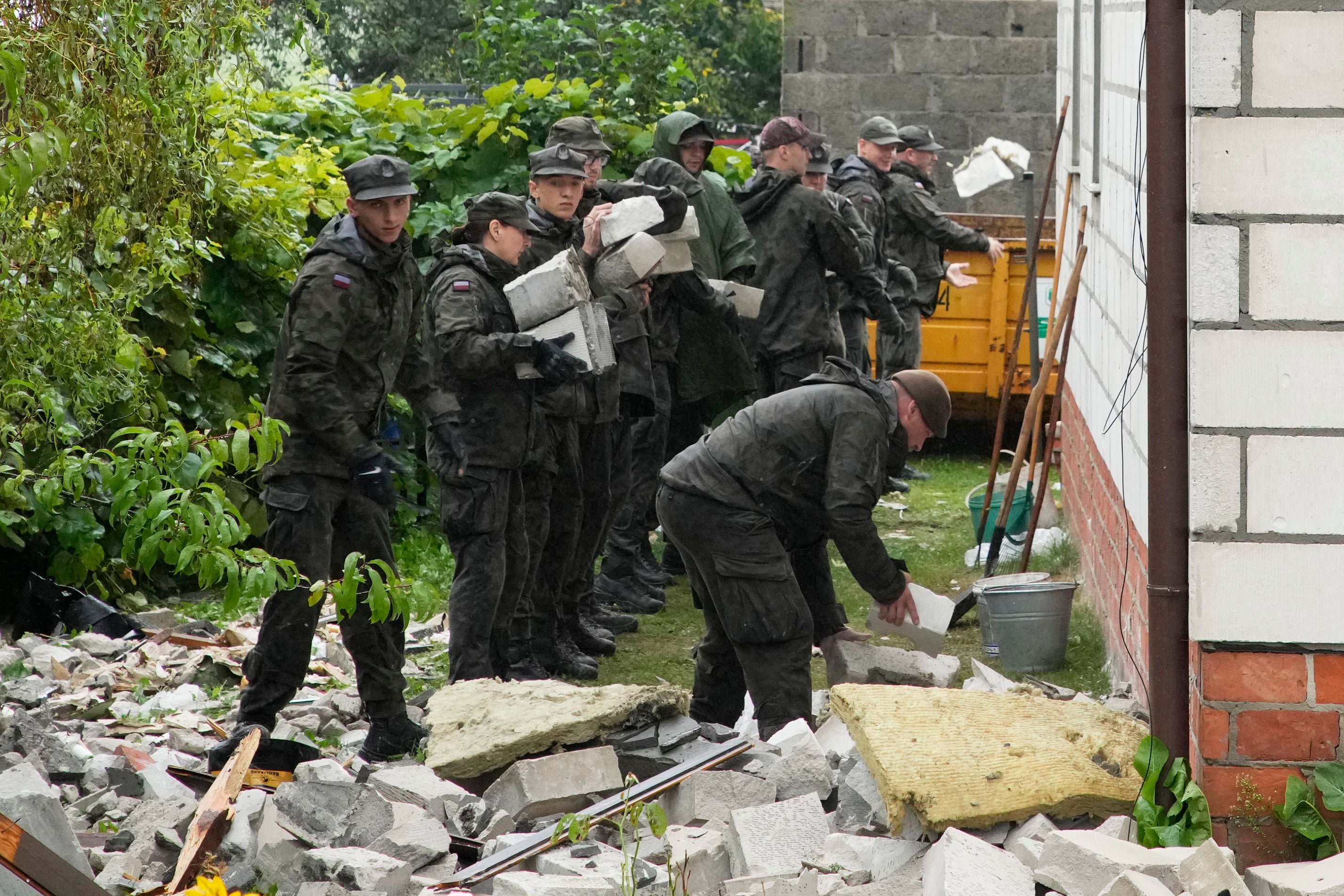 Territorial defence officers clean up debris from the destroyed roof of a house, after multiple Russian drones struck, in Wyryki near Lublin, Poland, on Thursday