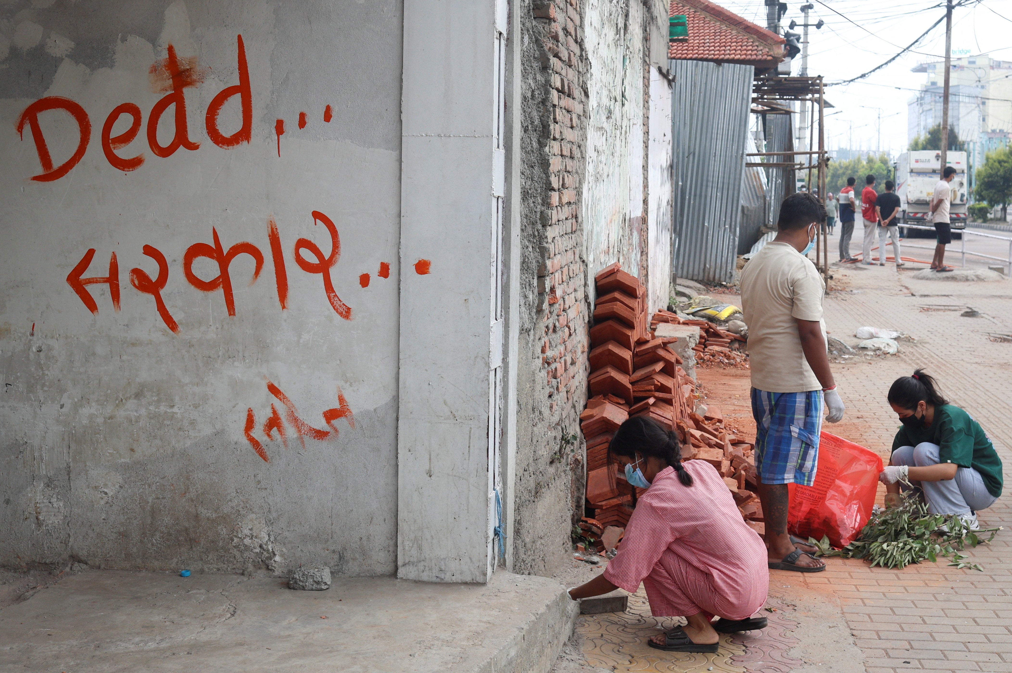 People clean a street next to graffiti that reads ‘dead government’