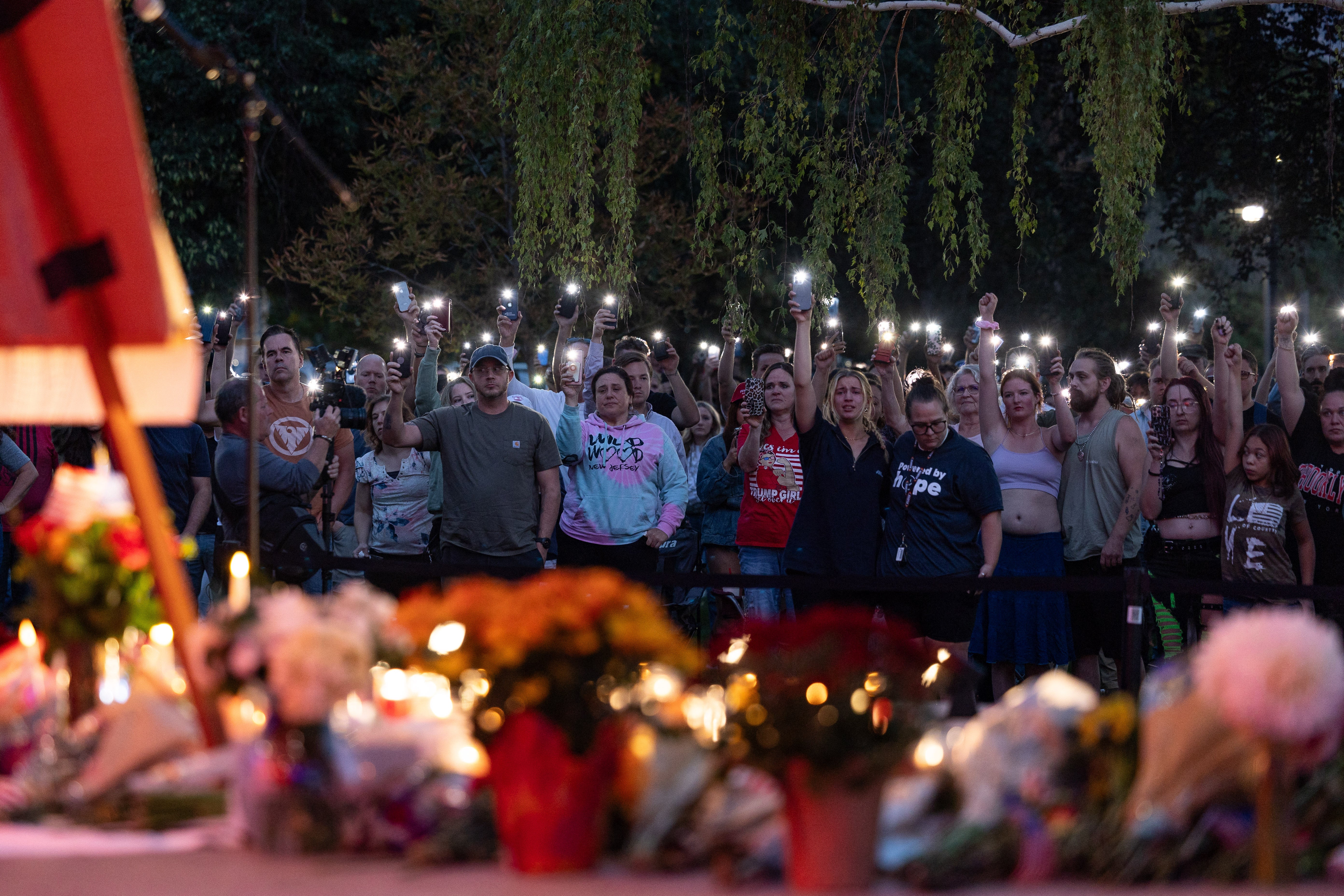 People pay their respects during a candlelight vigil for youth activist and influencer Charlie Kirk at a makeshift memorial at Orem City Center Park