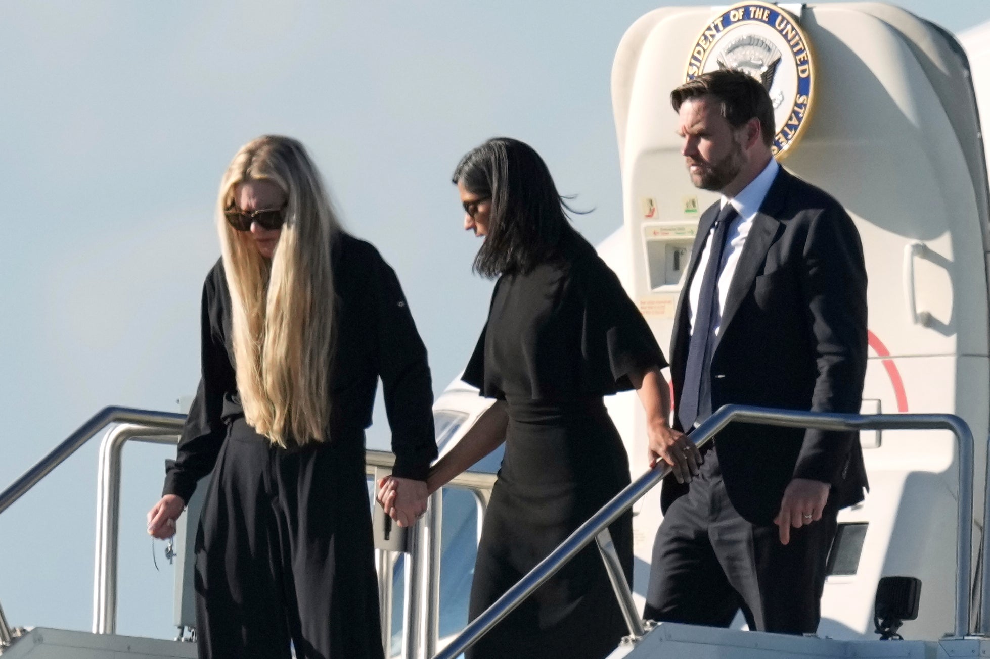 Vice President JD Vance, right, Second Lady Usha Vance, center, and Erika Kirk, holding a cross on a chain, deplane Air Force Two, carrying the body of Charlie Kirk