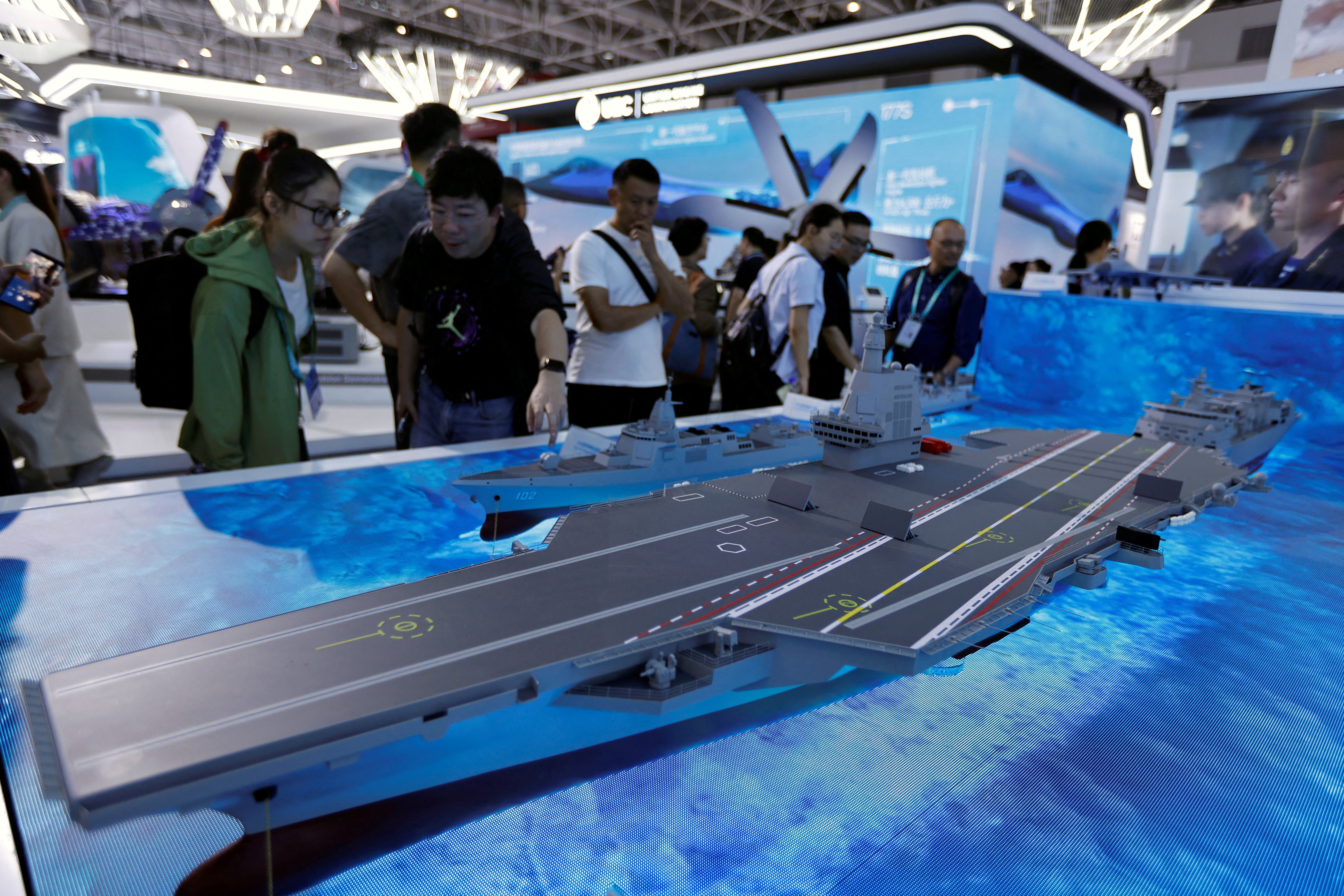 Visitors look at a model of the Fujian Type 003 aircraft carrier displayed at the China International Aviation and Aerospace Exhibition