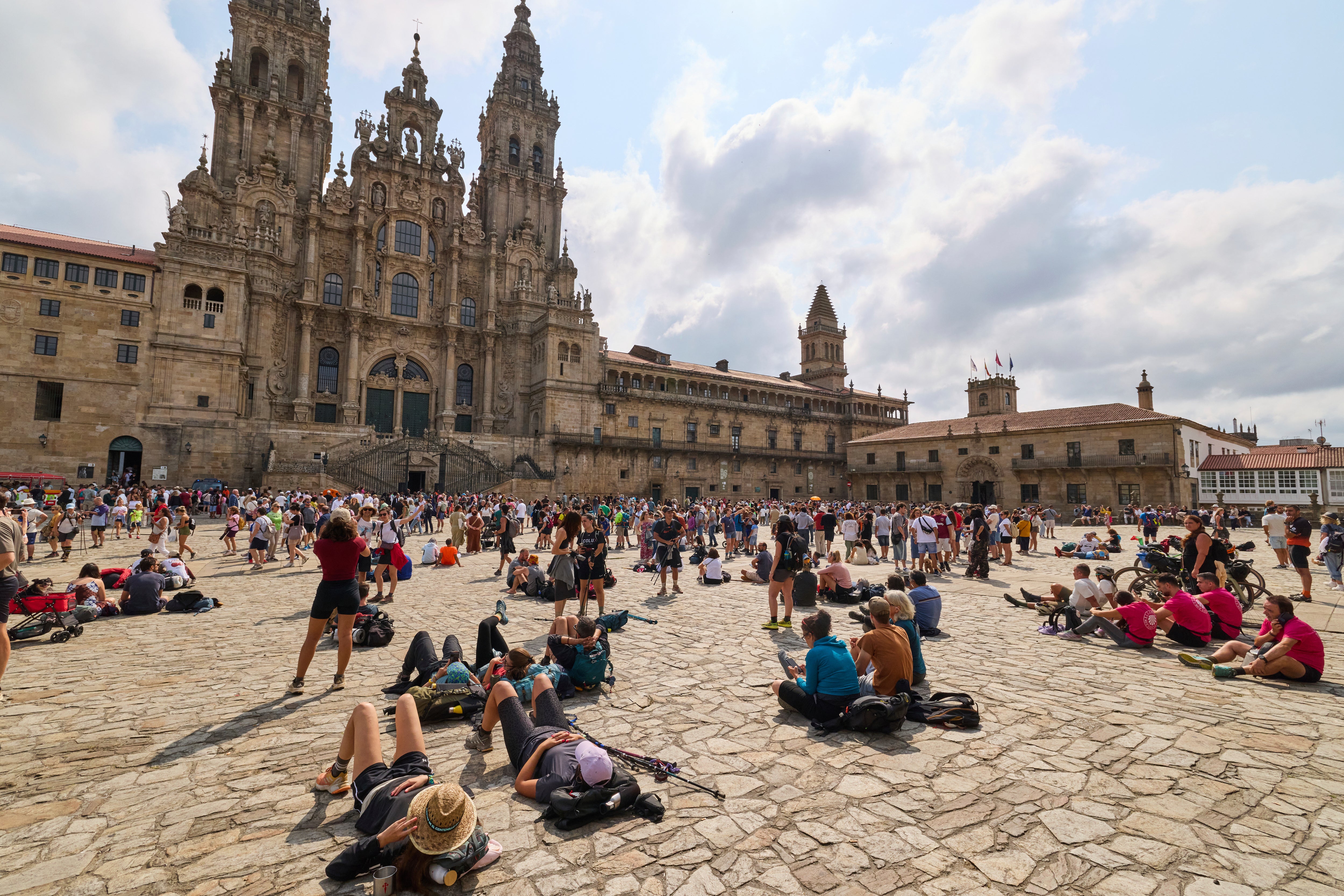 Pilgrims and tourists rest in front of the cathedral in Santiago de Compostela, northwestern Spain, Thursday, Aug. 21, 2025. (AP Photo/Lalo Villar)