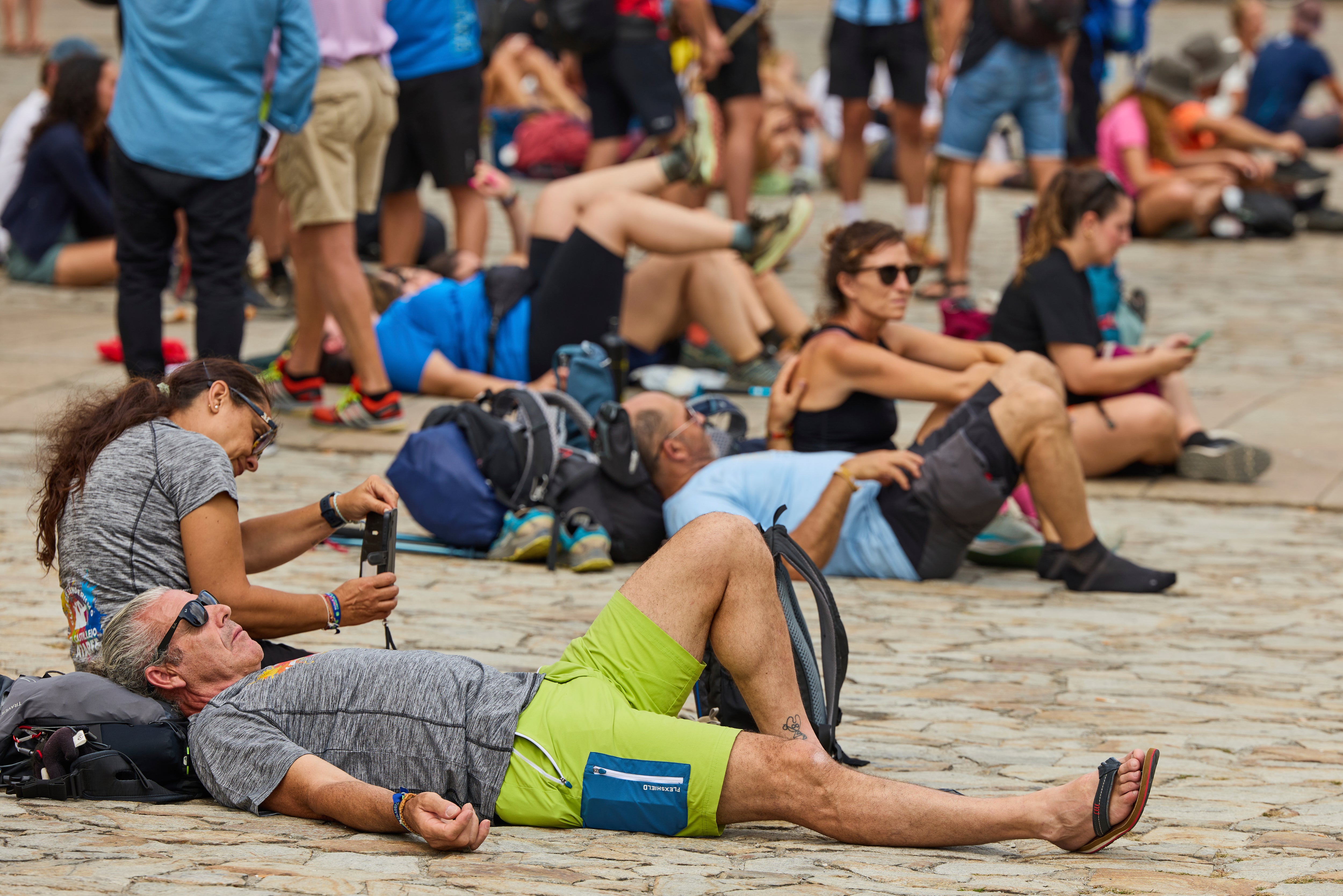 Pilgrims and tourists rest in front of the cathedral in Santiago de Compostela, northwestern Spain, Thursday, Aug. 21, 2025. (AP Photo/Lalo Villar)