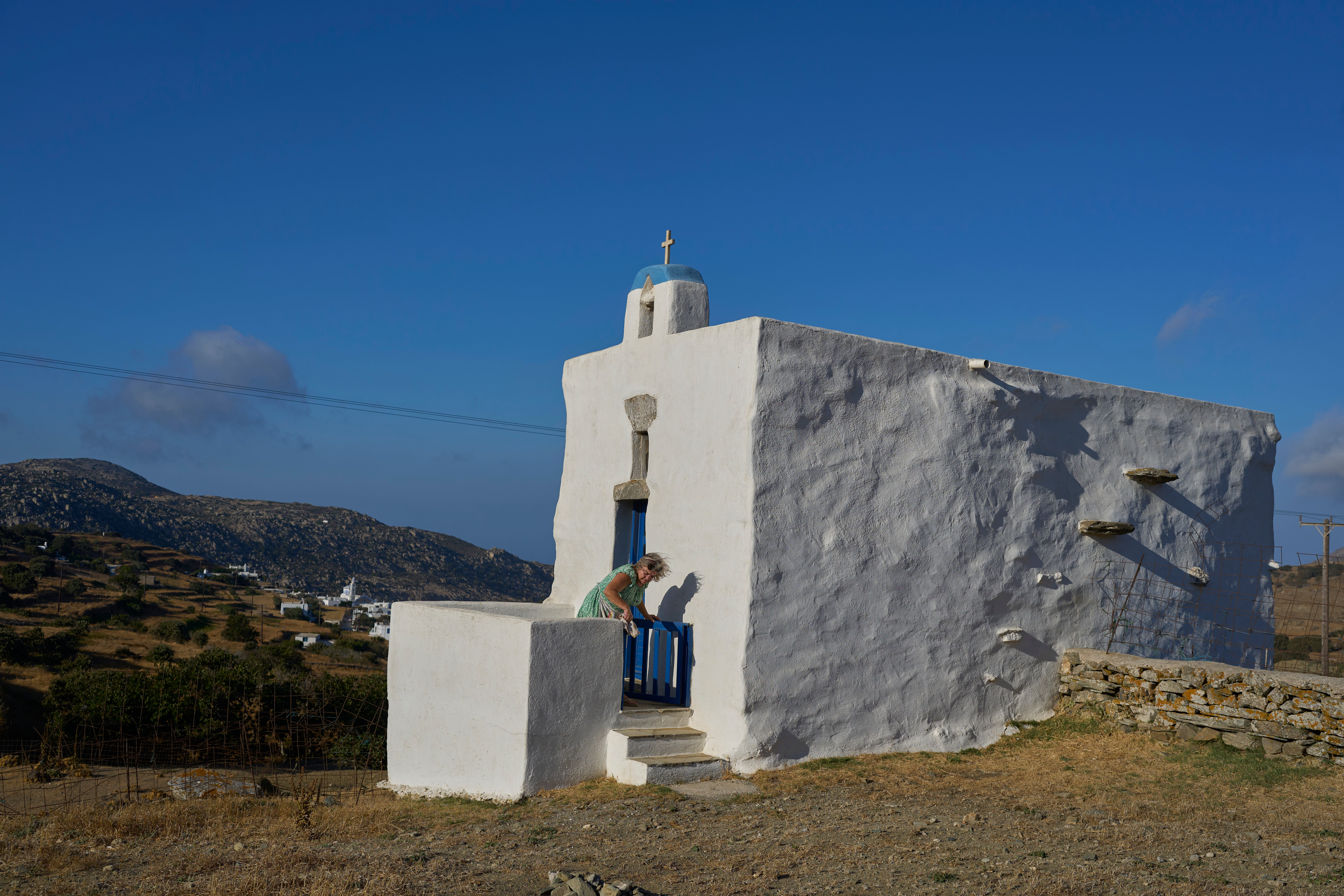 Bernadette Foskolos cleans her Agios Athanasios family-owned chapel at the village of Steni, on the island of Tinos, Greece, Saturday, Sept. 6, 2025. (AP Photo/Petros Giannakouris)