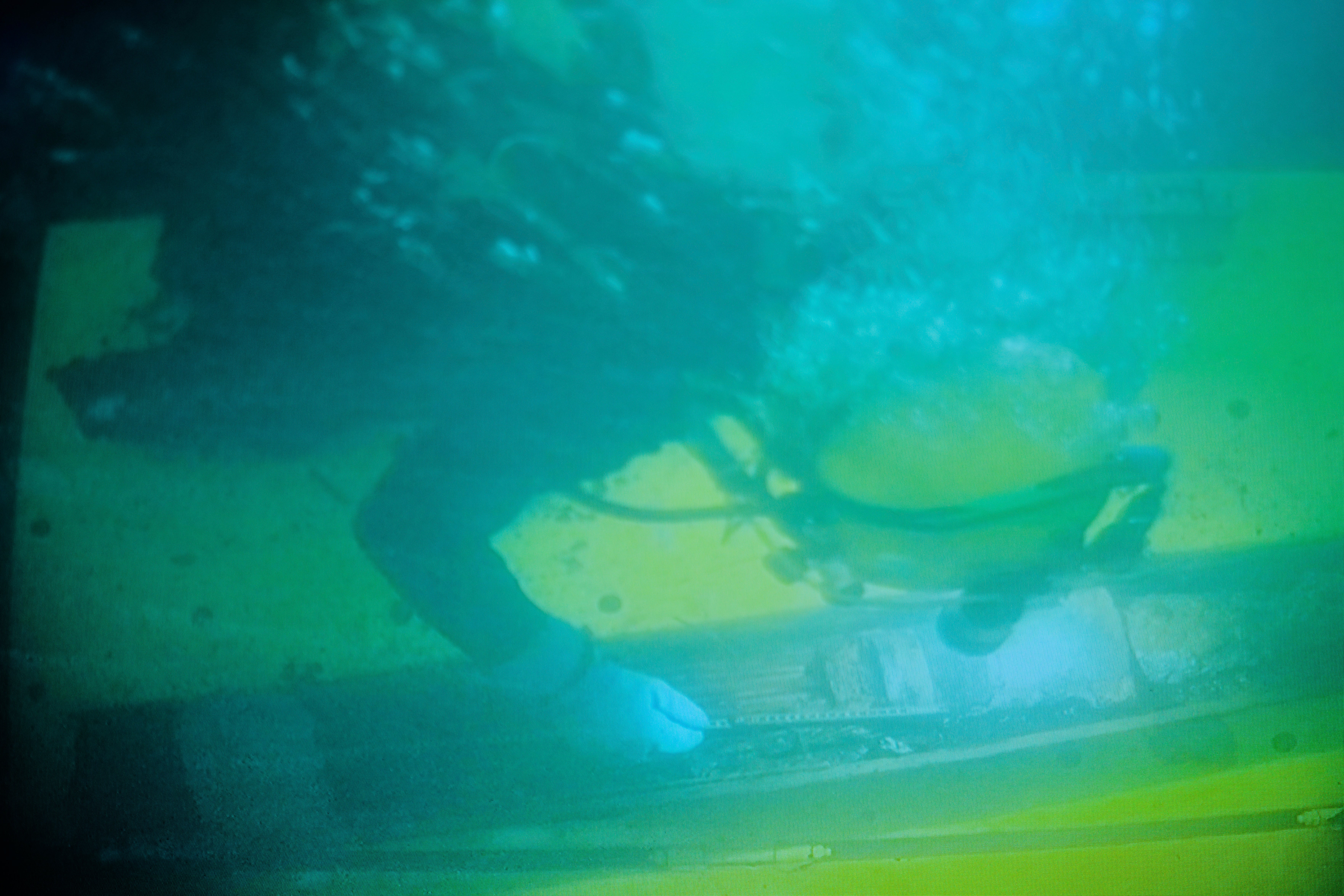 A diver works on a 128-millimeter artillery grenade during a press tour to show the recovering of ammunition from World War II in the Baltic Sea