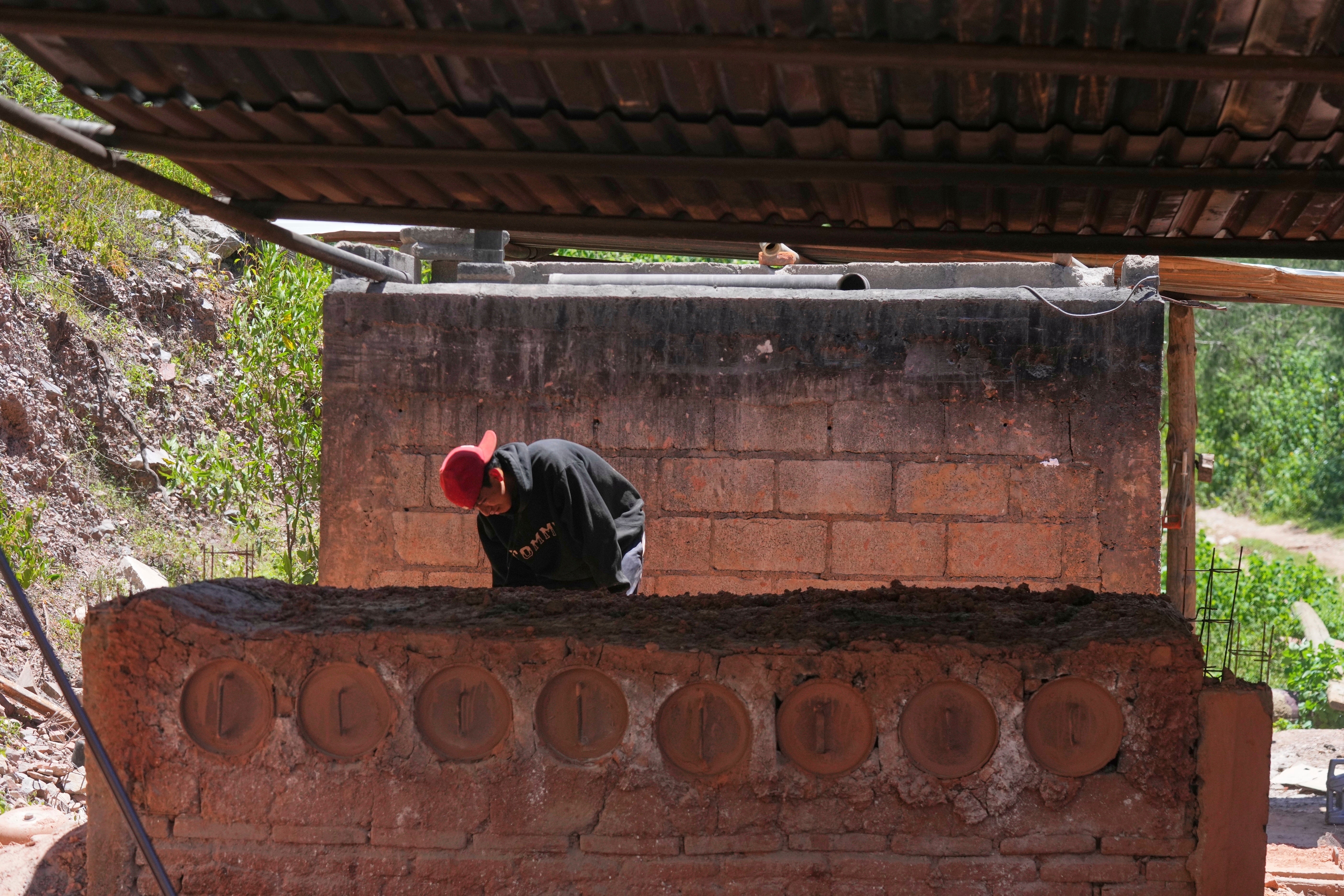 A miner checks for leaks in the pipes of a furnace where mercury is cooked