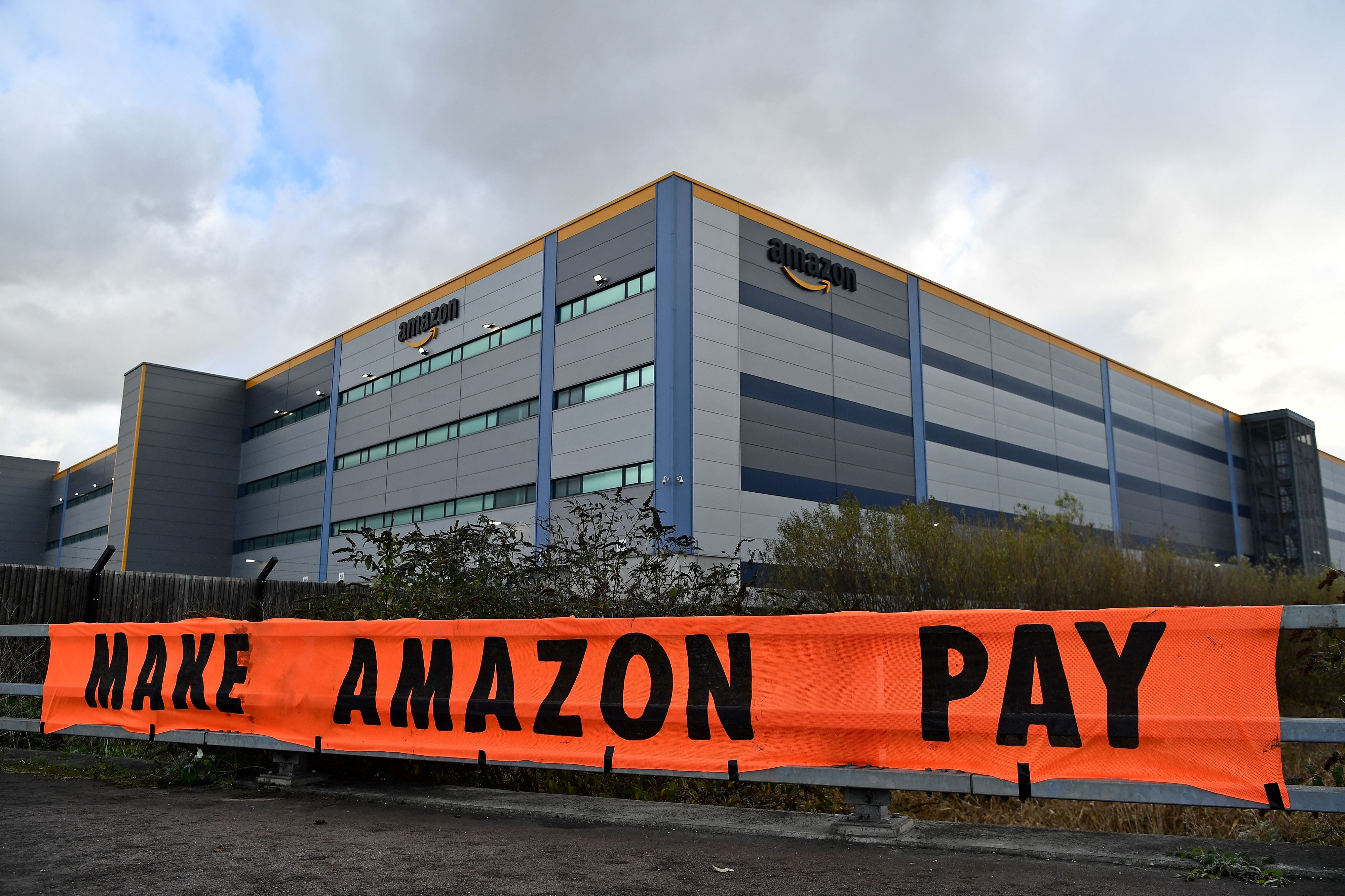 Activists from the Extinction Rebellion climate change group block the exit to an Amazon distribution centre during a protest in Tilbury, east of London, in 2021