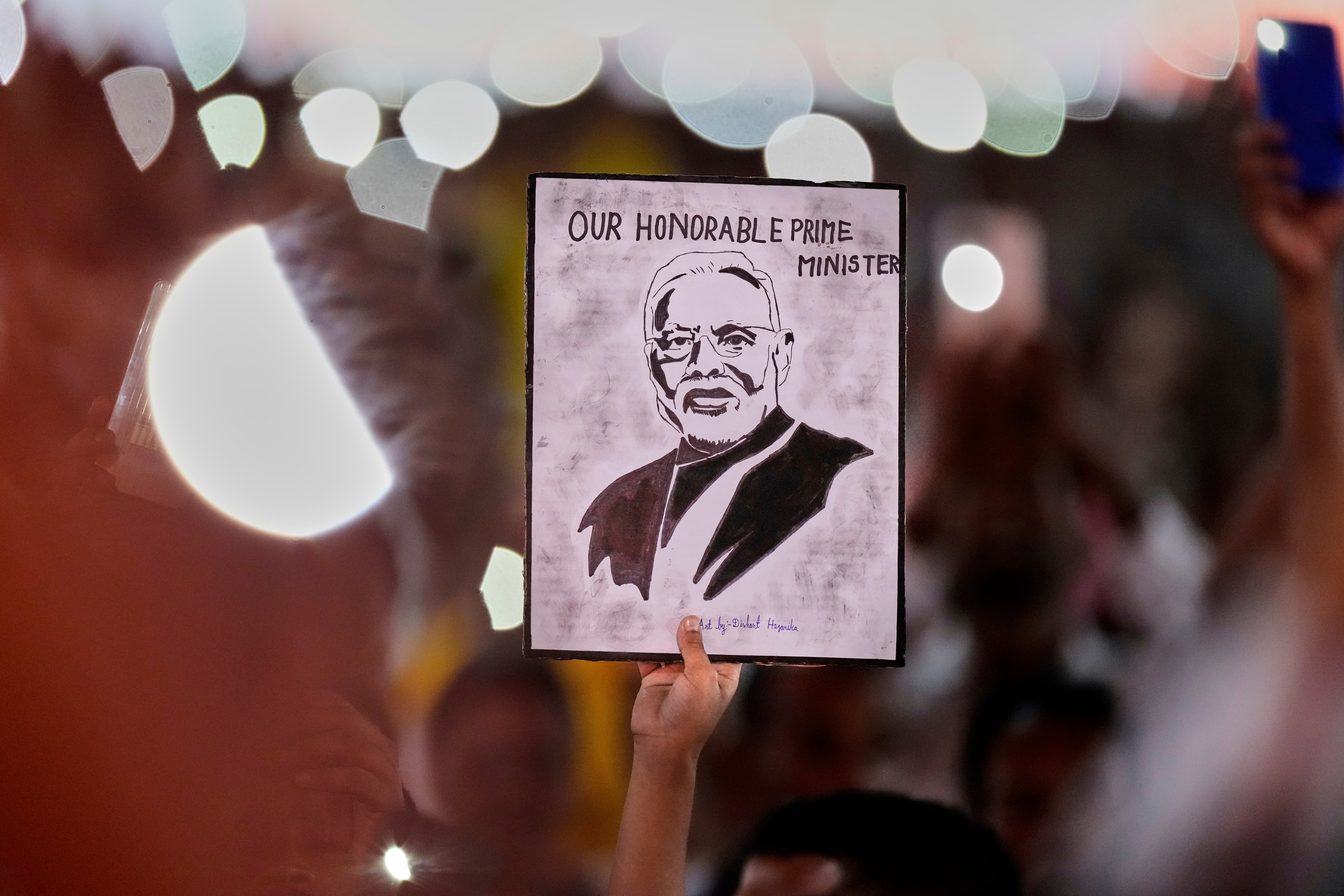 A supporter holds a painting of Indian prime minister Narendra Modi as he delivers his speech during a public rally at Mangaldoi, north of Guwahati, India