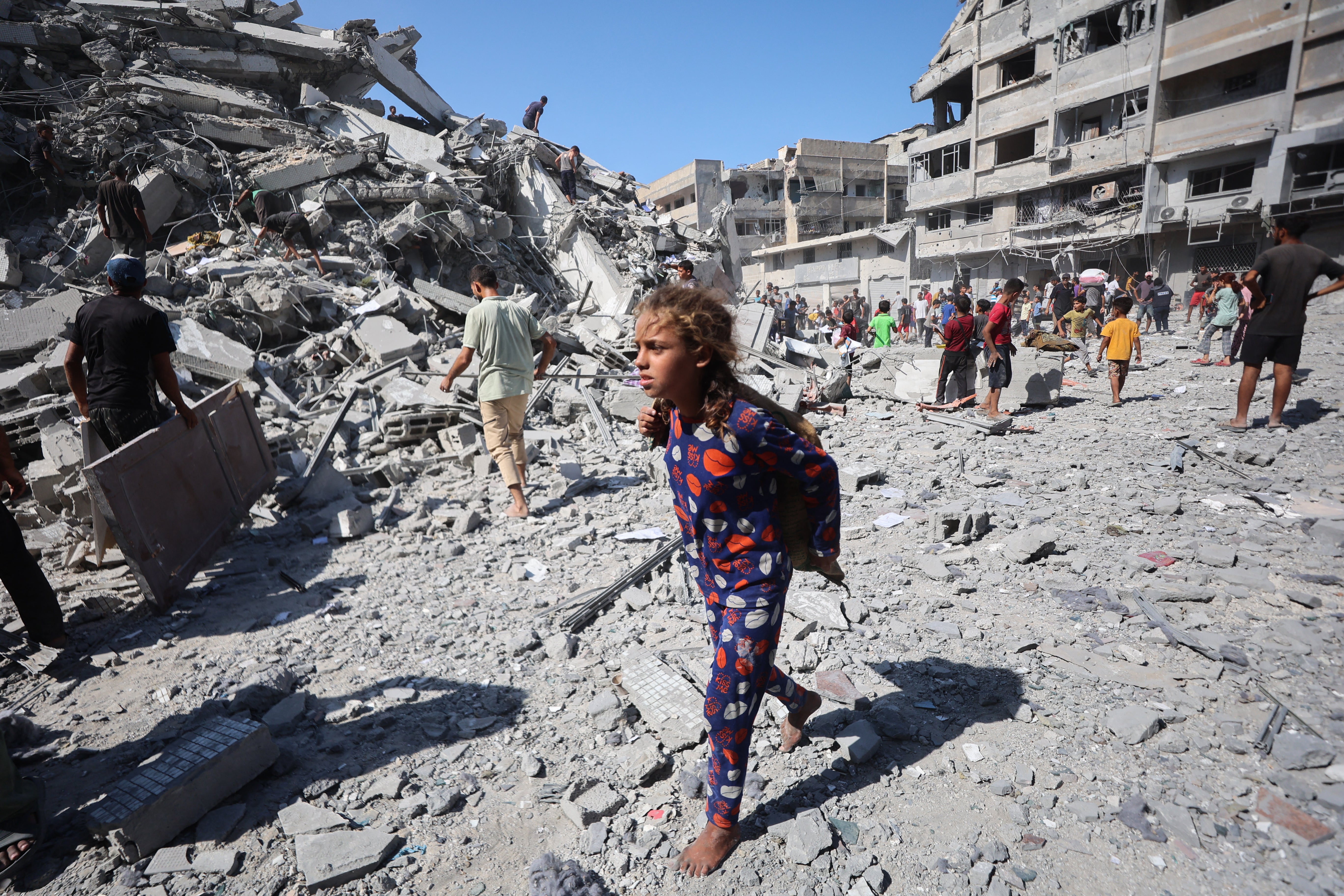 Displaced Palestinians salvage items from the rubble of the al-Ghafari tower on Monday