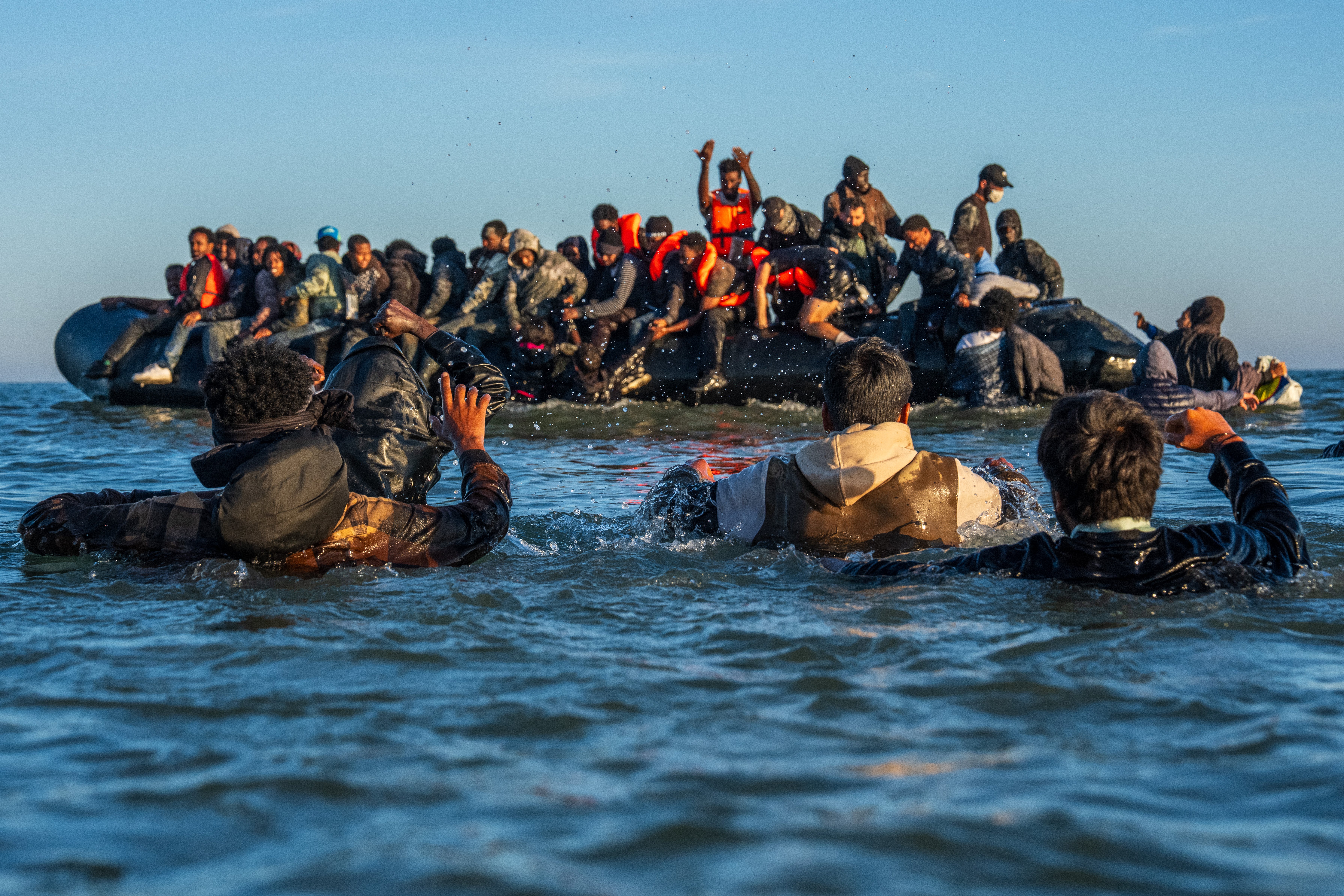 Migrants wade in deep water to board a dinghy in the English Channel last month off the coast of Gravelines, France