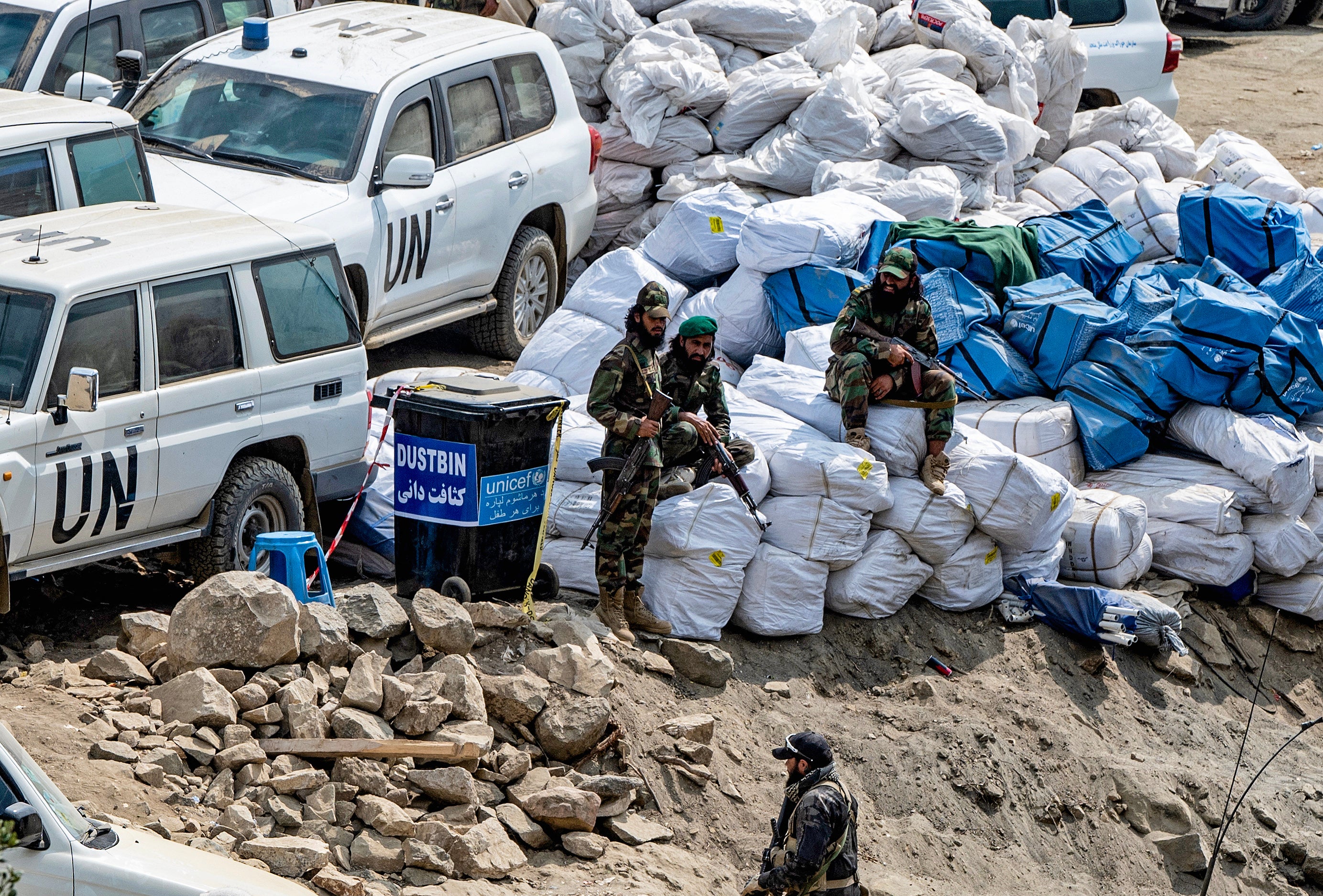 Afghan security personnel watch sacks of relief aid kept beside UN official vehicles in the aftermath of an earthquake at Mazar Dara village in Nurgal district