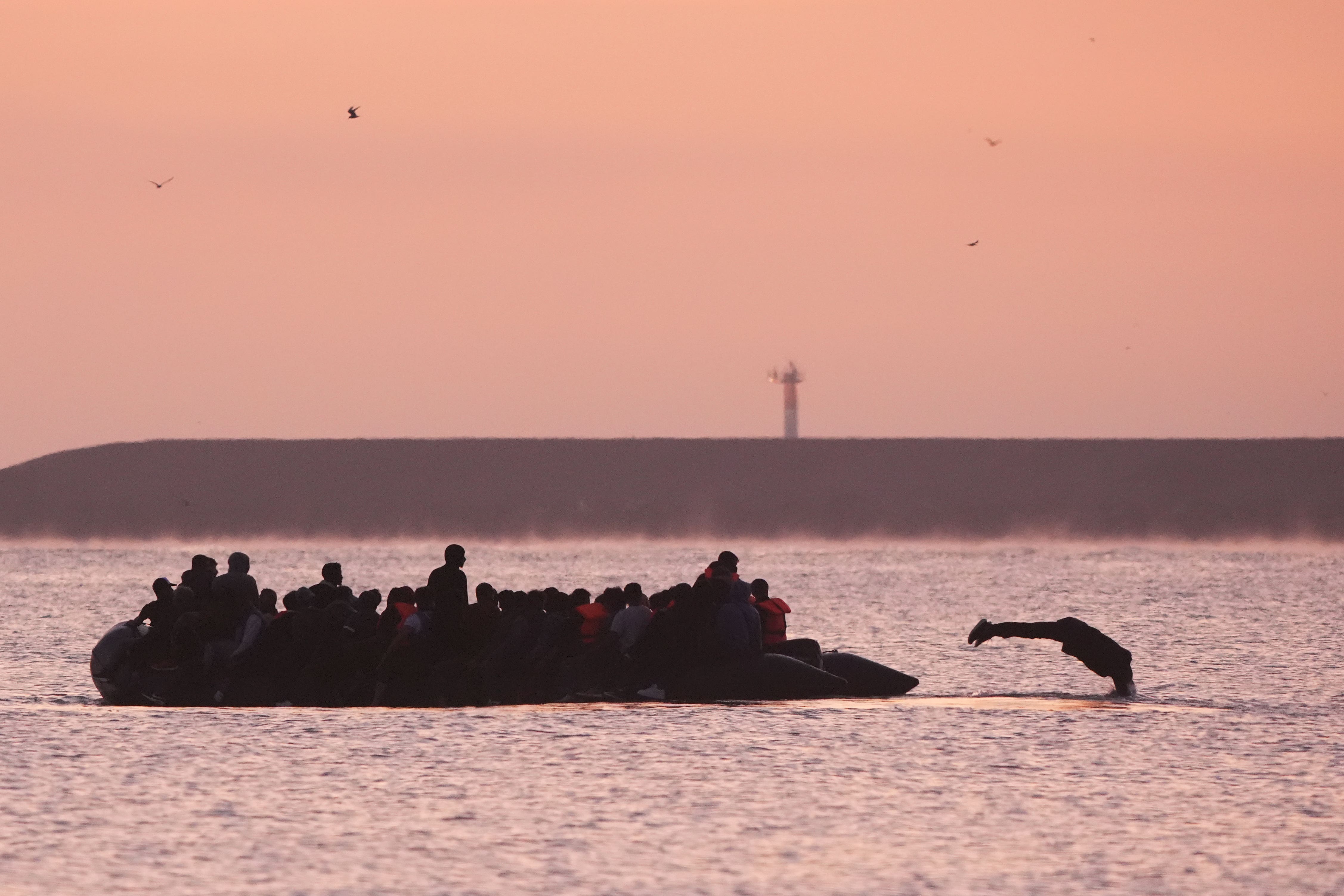 A small boat carrying people thought to be migrants arrives to collect more people in Gravelines, France (Gareth Fuller/PA)