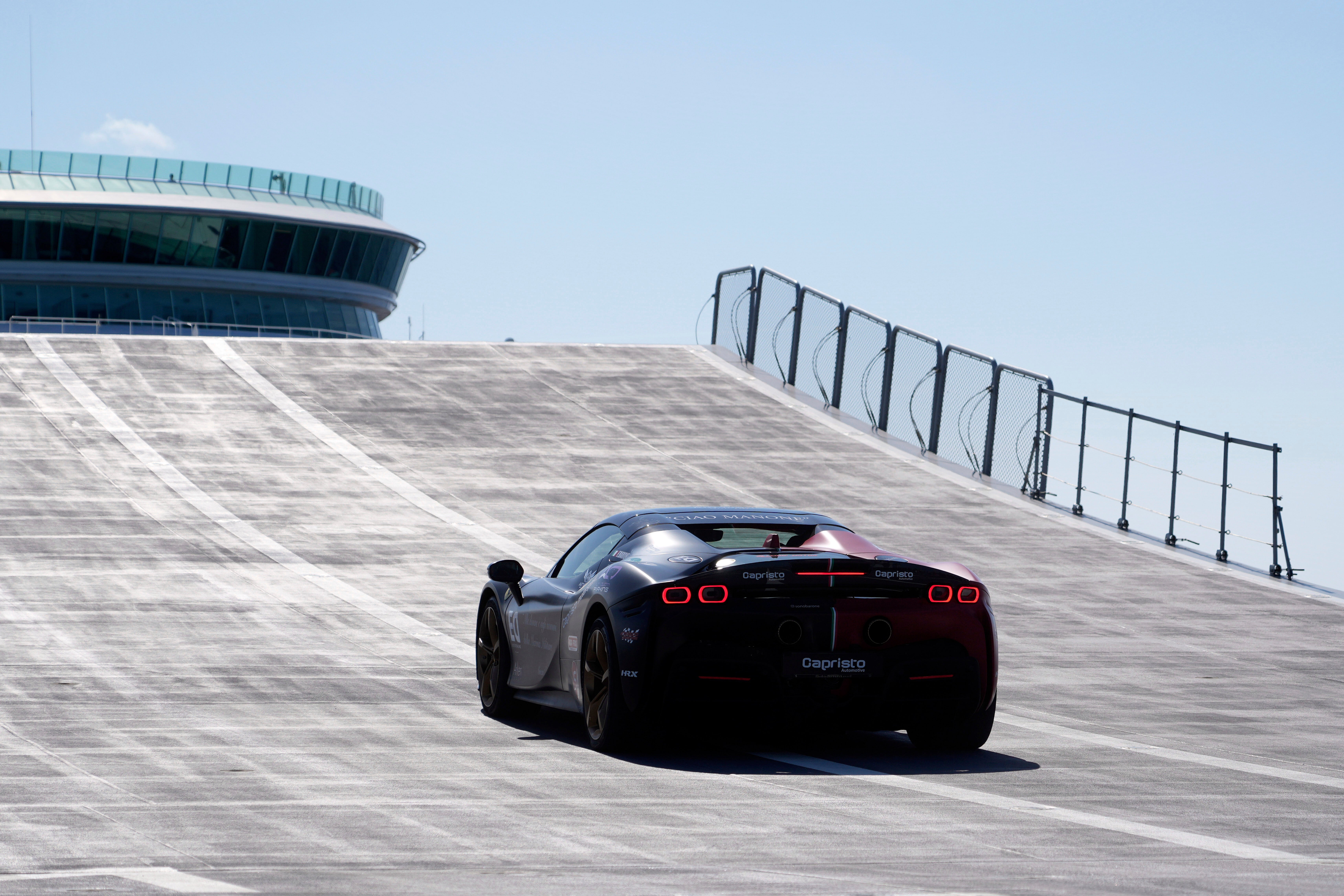 Italian driver Fabio Barone attempts to break his own speed record on a ship, at the wheel of a Ferrari SF 90, on the flight deck of the Italian Navy aircraft carrier Nave Trieste, docked at the port of Civitavecchia, Thursday, Sept. 18, 2025. (AP Photo/Gregorio Borgia)