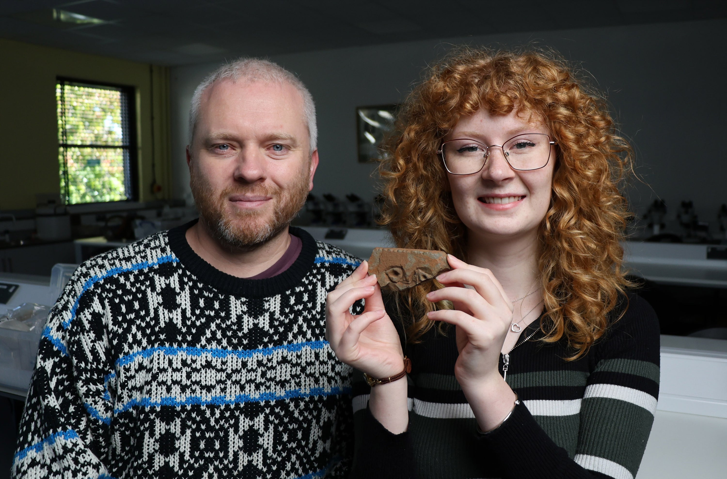 Jodie Allan, with Professor Gordon Noble (left), holding what is thought may be a rare carving of a Pict's face she discovered while volunteering on a dig at East Lomond hill fort in Fife