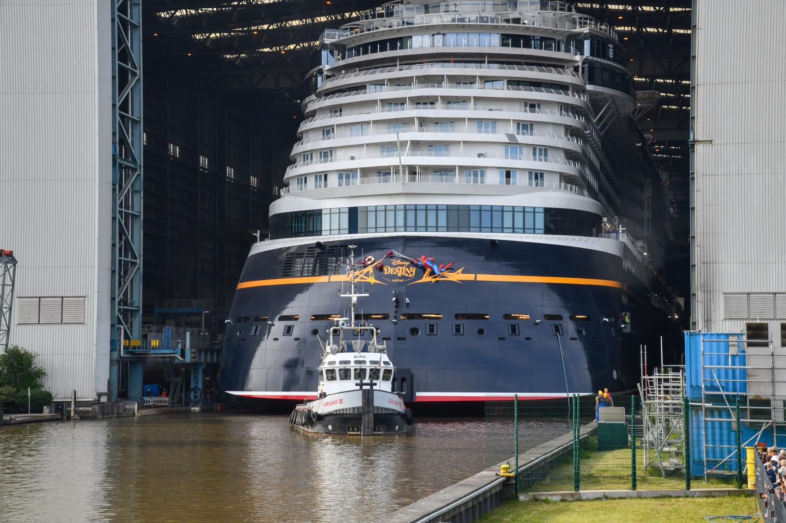 A tugboat pulls Disney Destiny out from the Meyer Werft dry dock for its float-out ceremony