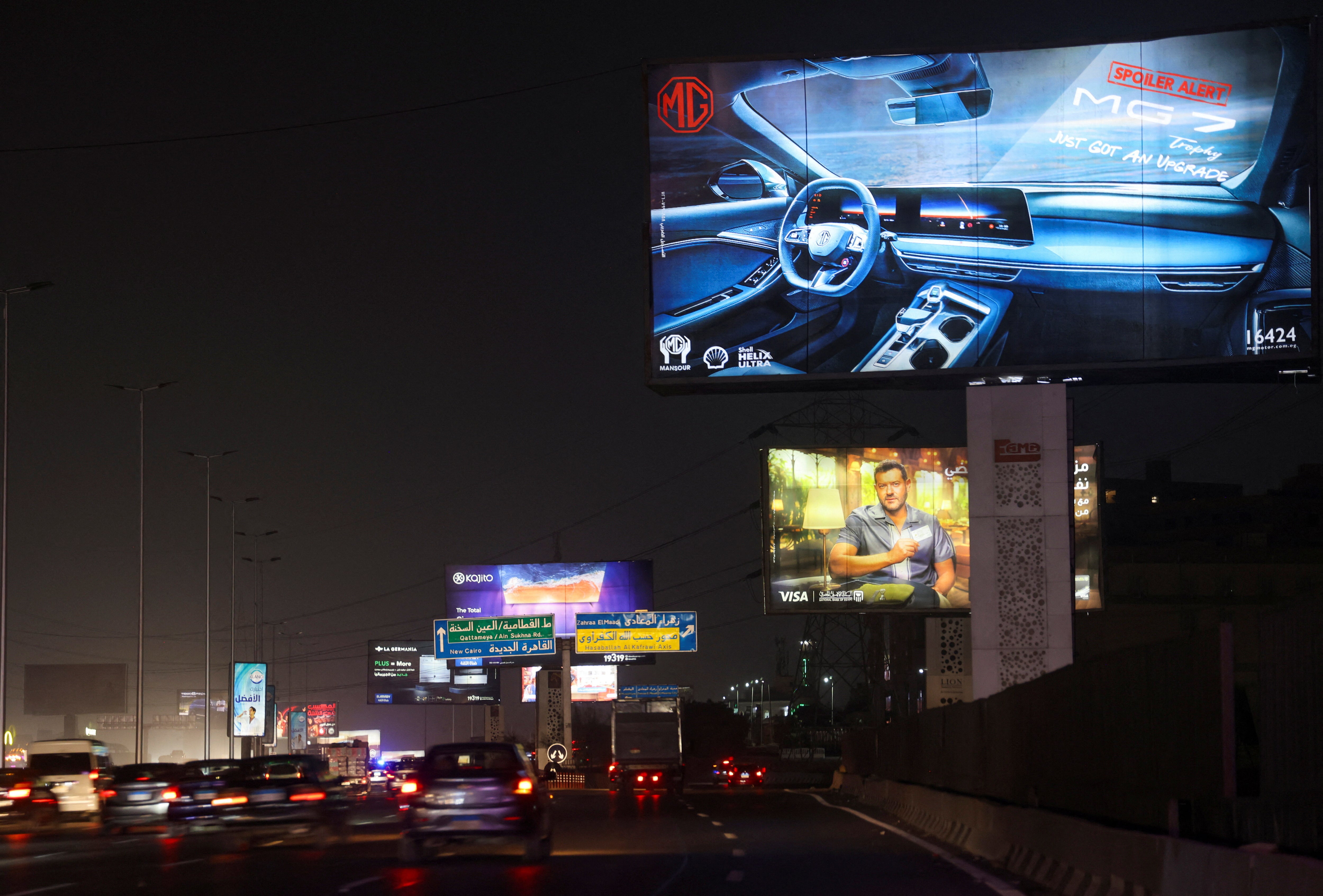 Vehicles drive past brightly lit billboards in Cairo, Egypt