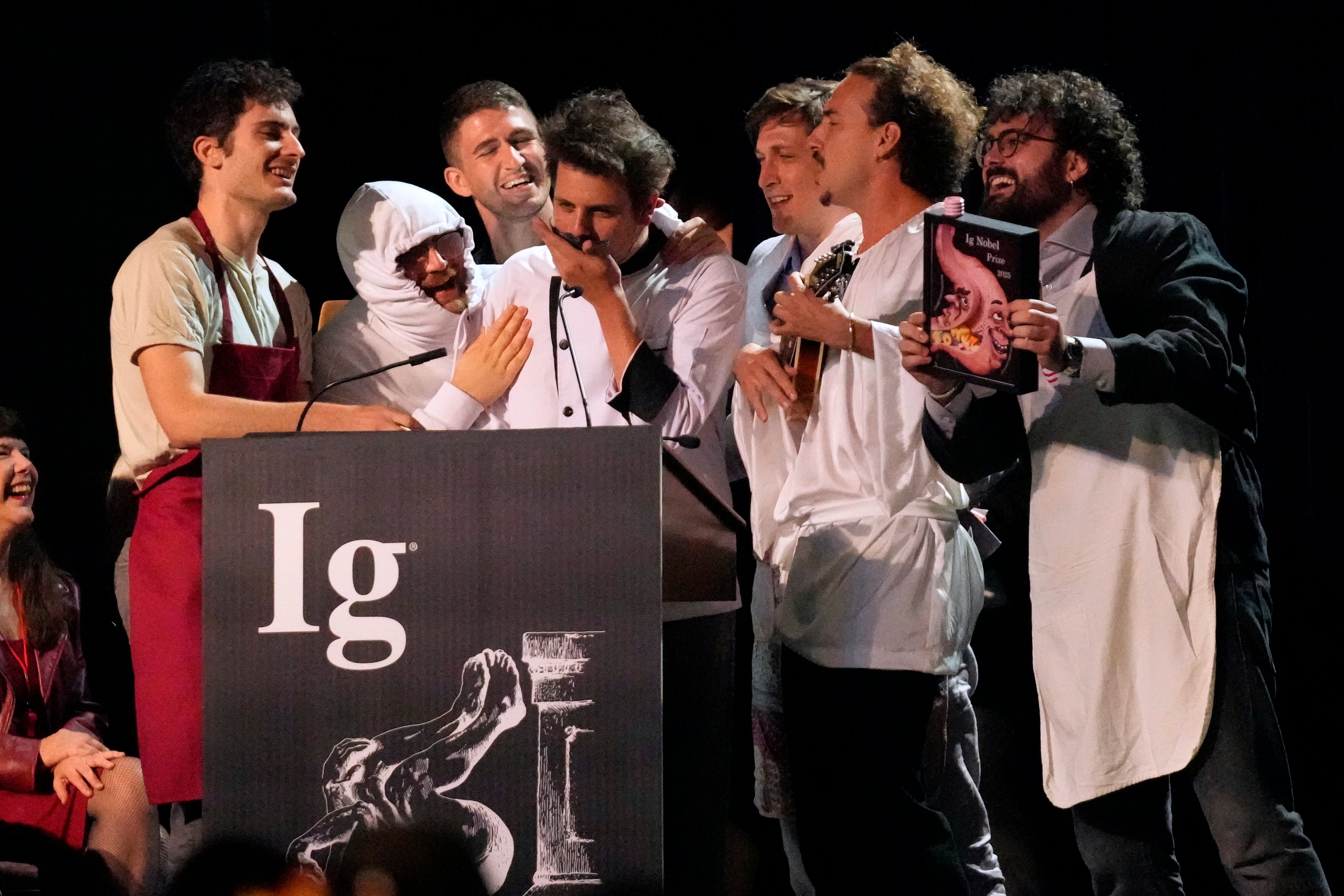 The Ig Nobel Prize for nutrition is accepted by Daniele Dendi, Gabriel H. Segniagbeto, Roger Meek, and Luca Luiselli, for studying the extent to which a certain kind of lizard chooses to eat certain kinds of pizza