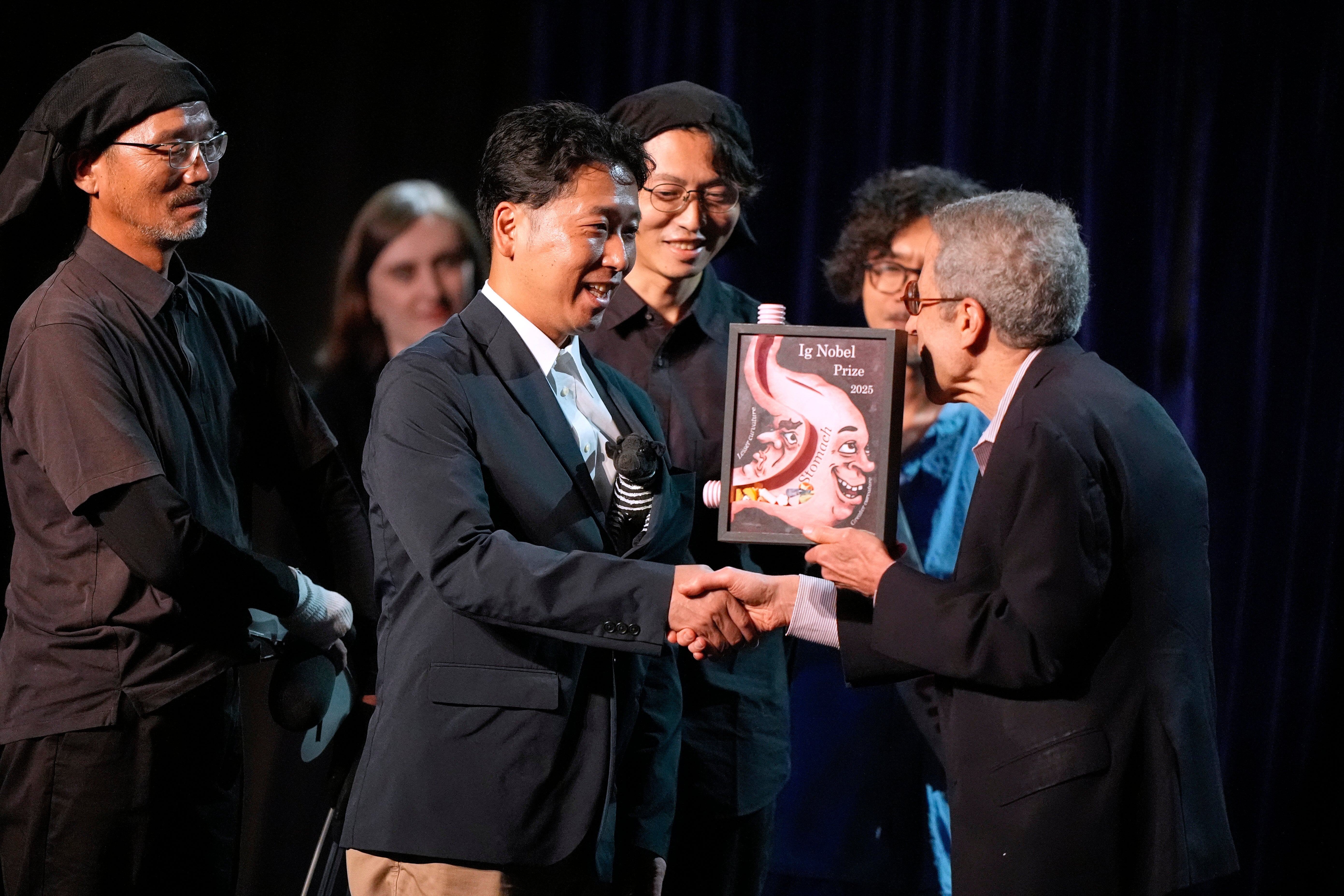 The Ig Nobel Prize for biology is accepted by researchers Tomoki Kojima, Kazato Oishi, Yasushi Matsubara, Yuki Uchiyama, Yoshihiko Fukushima, Naoto Aoki, Say Sato, Tatsuaki Masuda, Junichi Ueda, Hiroyuki Hirooka, and Katsutoshi Kino, for their experiments to learn whether cows painted with zebra- like striping can avoid being bitten by flies