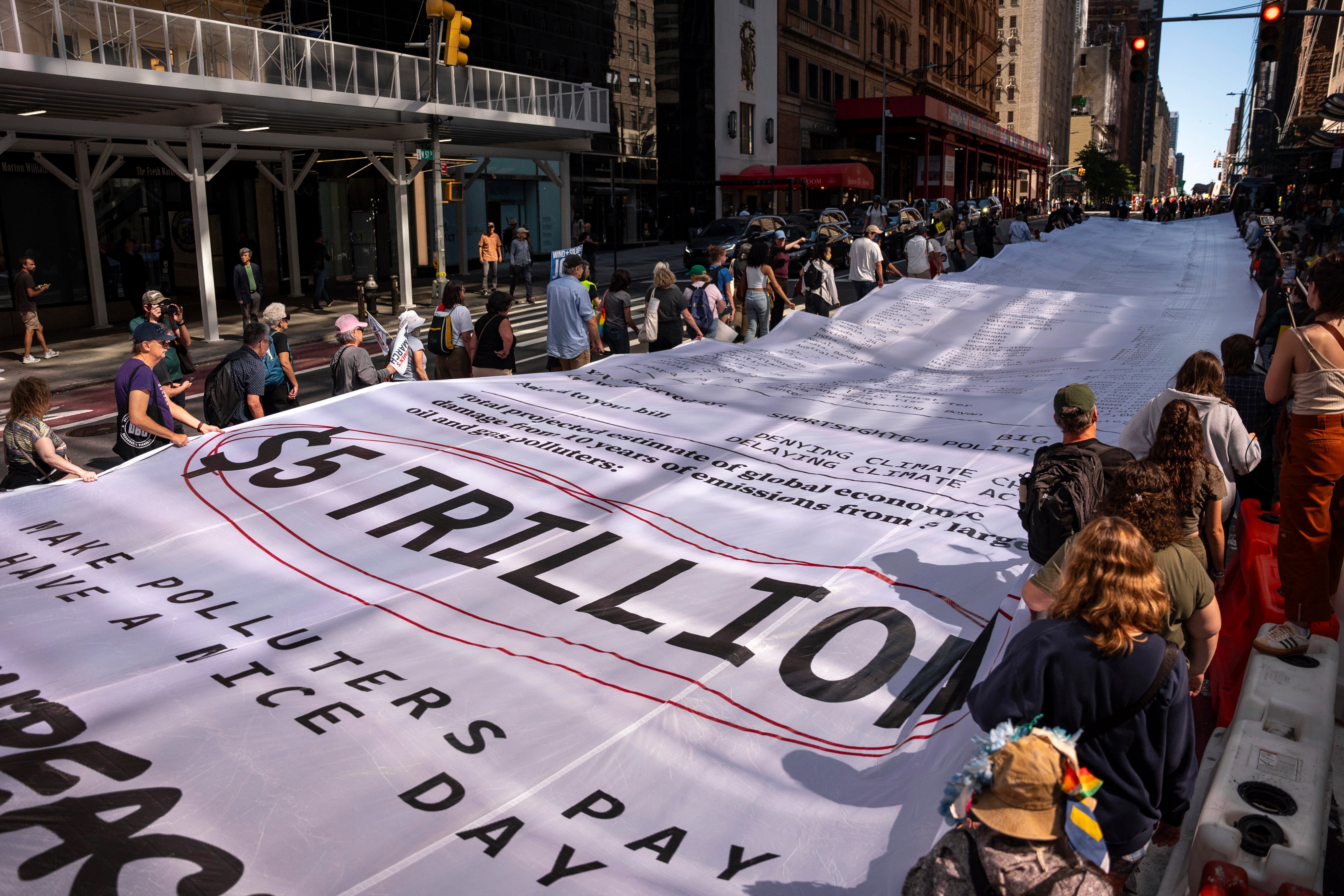People carry a "Climate Polluters Bill" the length of an Olympic swimming pool (50 meters long) through Manhattan at the "Make Billionaires Pay" climate protest