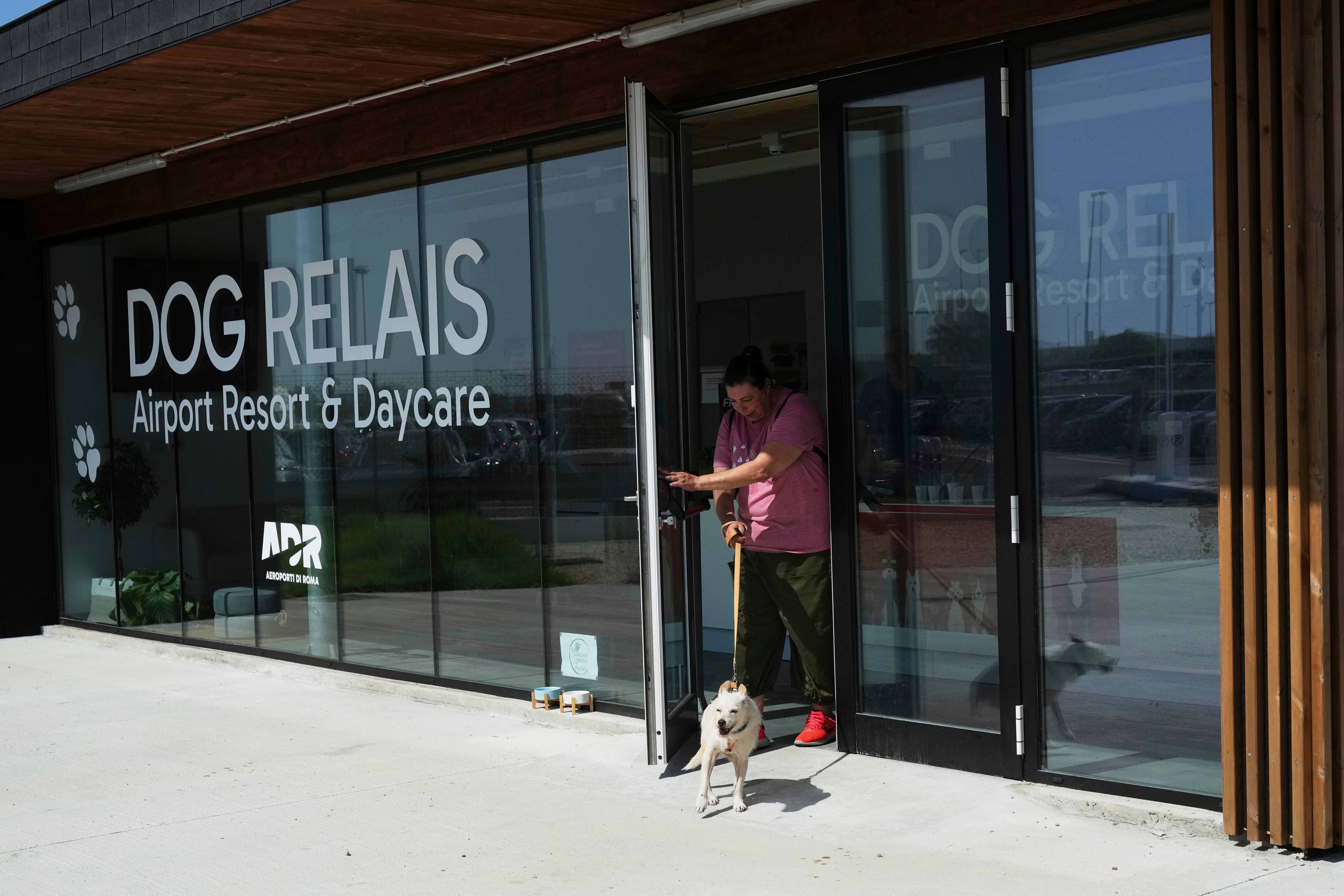 A costumer walks with her dog as she leaves the Dog Relais, a hotel for dogs at Rome's Fiumicino International Airport, Wednesday, Sept. 17, 2025. (AP Photo/Alessandra Tarantino)