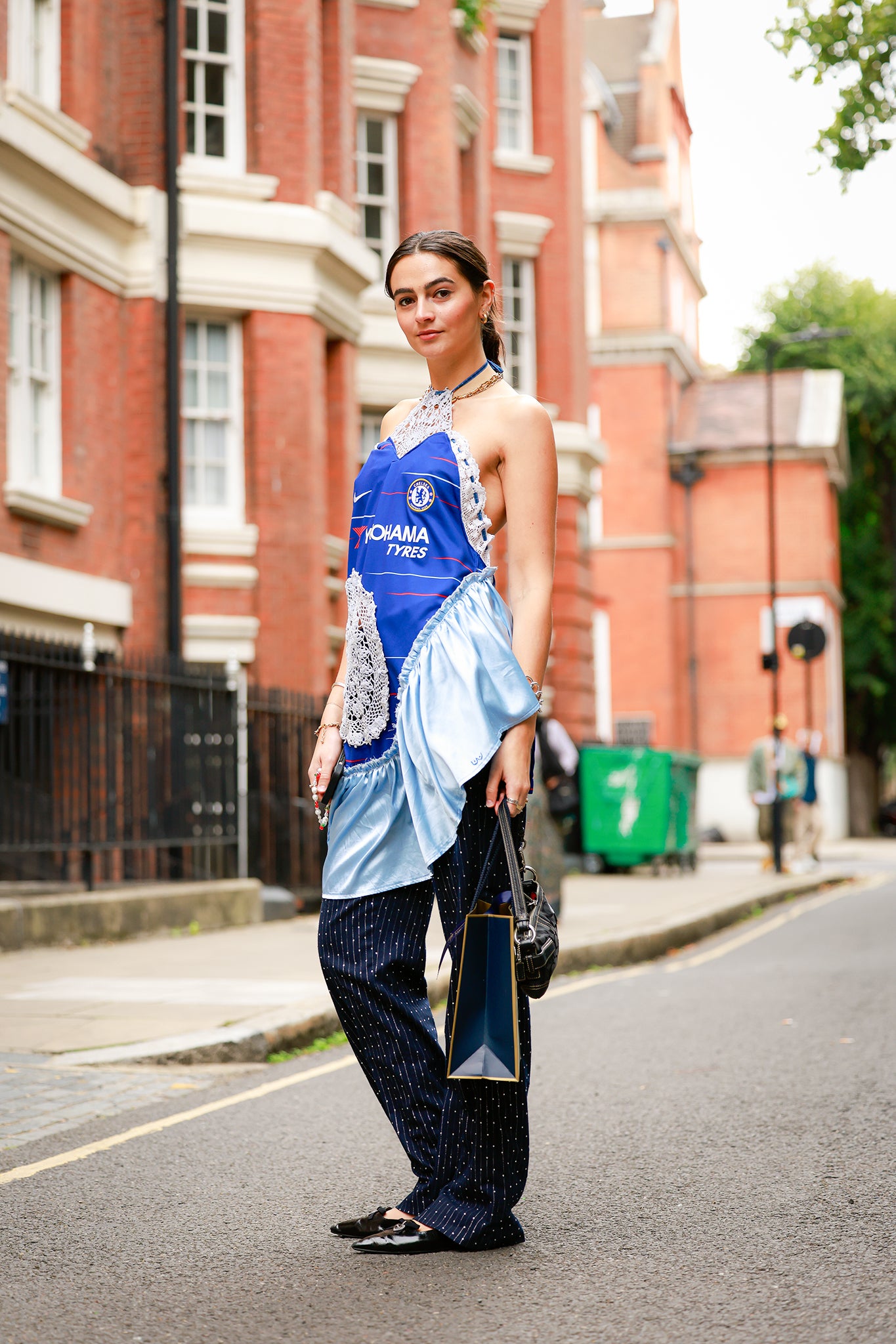 A guest wearing a blue sports jersey dress, navy dress, black flats and a black bag outside Yuhan Wang during London Fashion Week on 20 September 2025 (photo by Hanna Lassen/Getty Images)