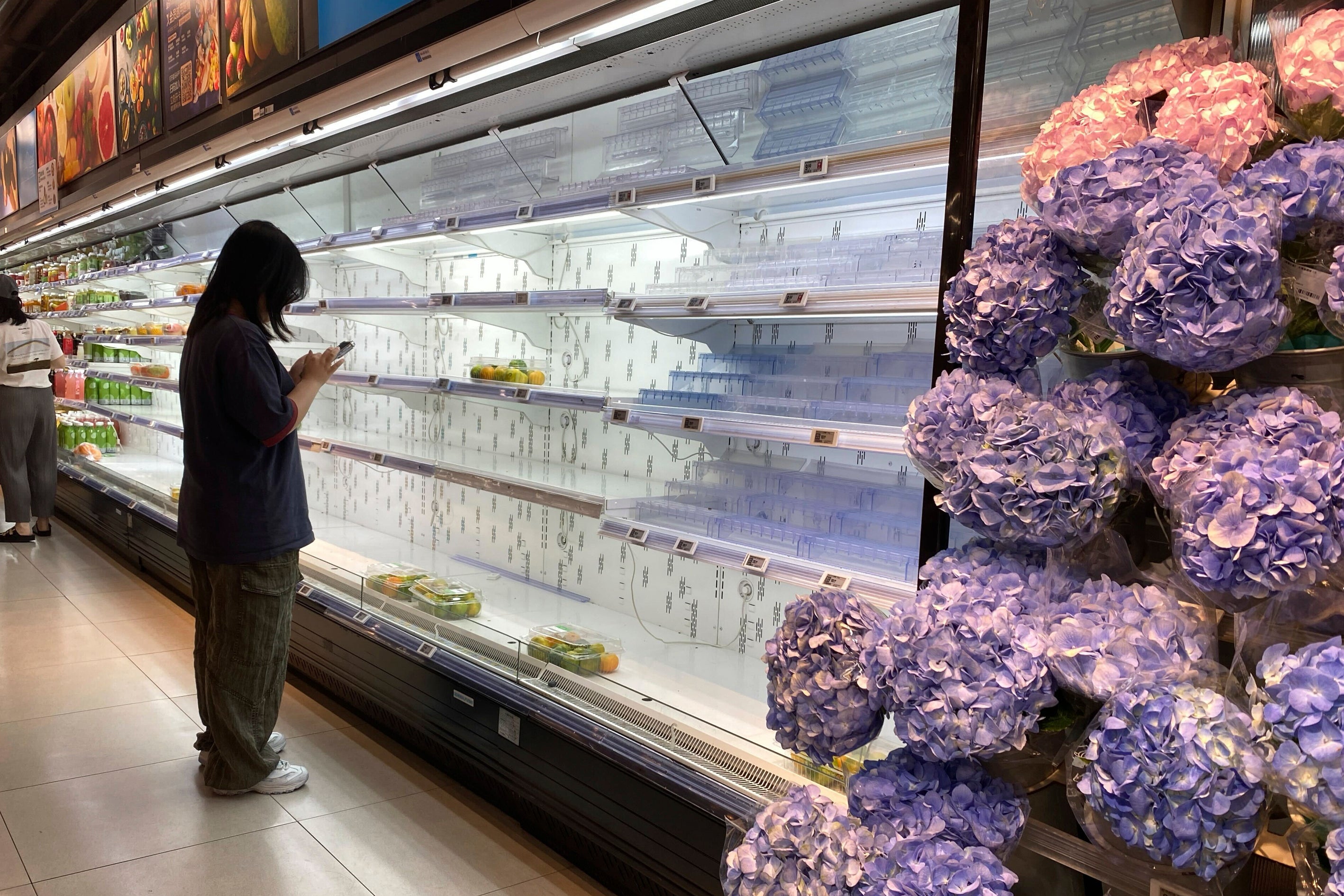 A shopper stands near near empty shelves at a supermarket ahead of Typhoon Ragasa in Shenzhen in southern China's Guangdong province