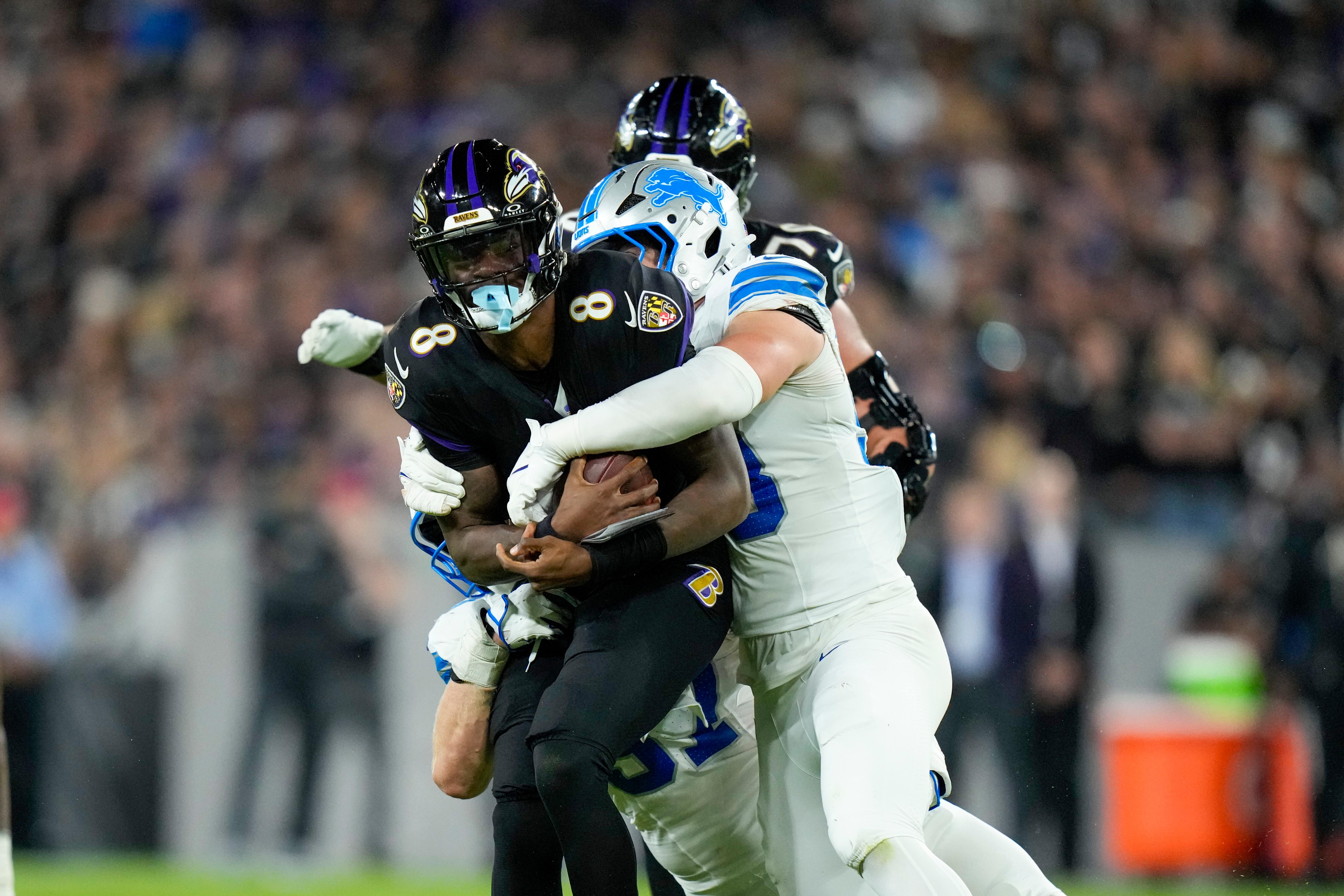 Baltimore Ravens quarterback Lamar Jackson (8) is brought down by Detroit Lions linebacker Trevor Nowaske, right, and defensive end Aidan Hutchinson, bottom, during the second half of an NFL football game (Stephanie Scarbrough/AP)