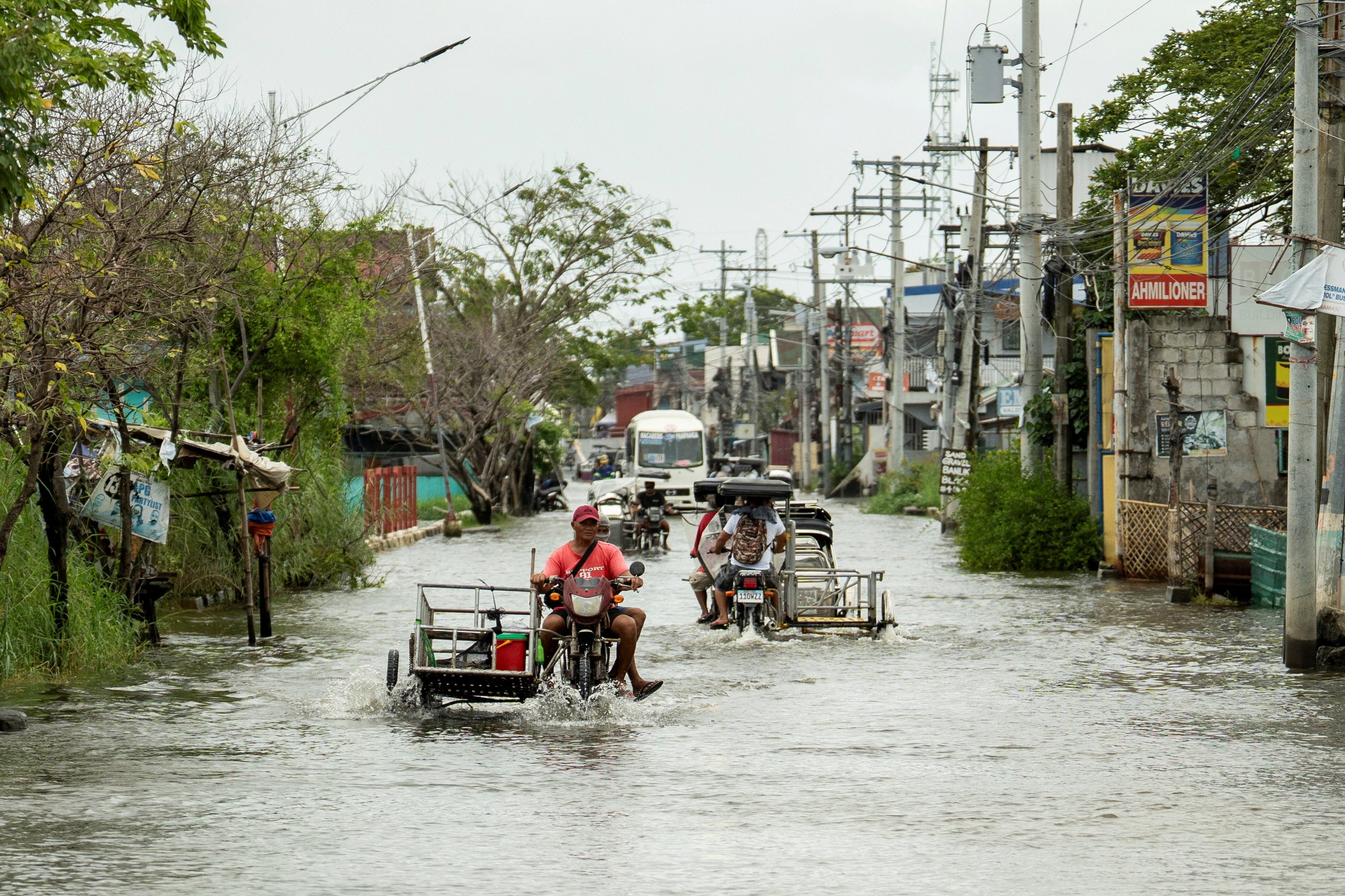 People navigate a flooded road following heavy rains intensified by Super Typhoon Ragasa in Apalit region of Pampanga province in the Philippines
