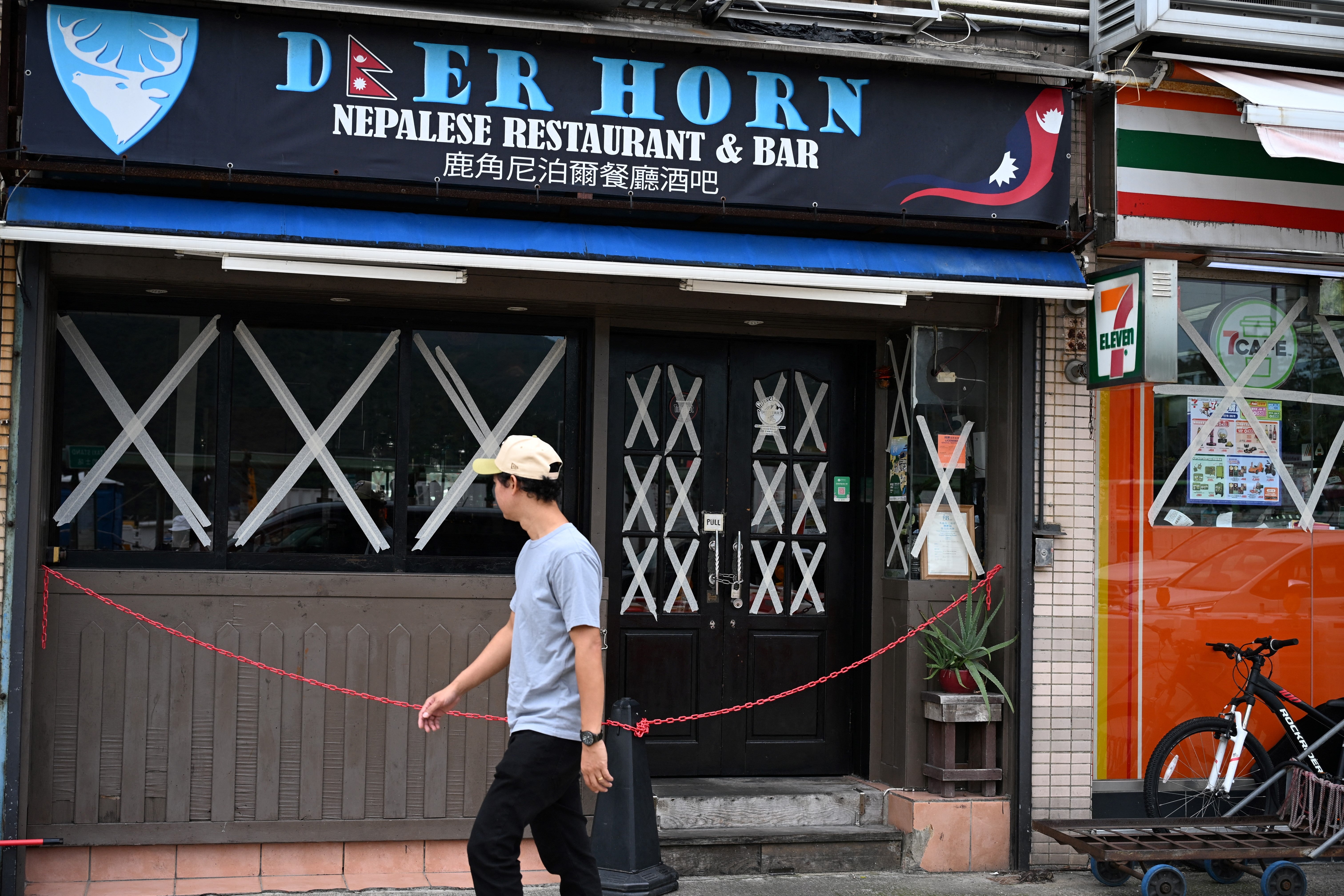 A man walks past a restaurant with sealed windows as Ragasa approaches Hong Kong