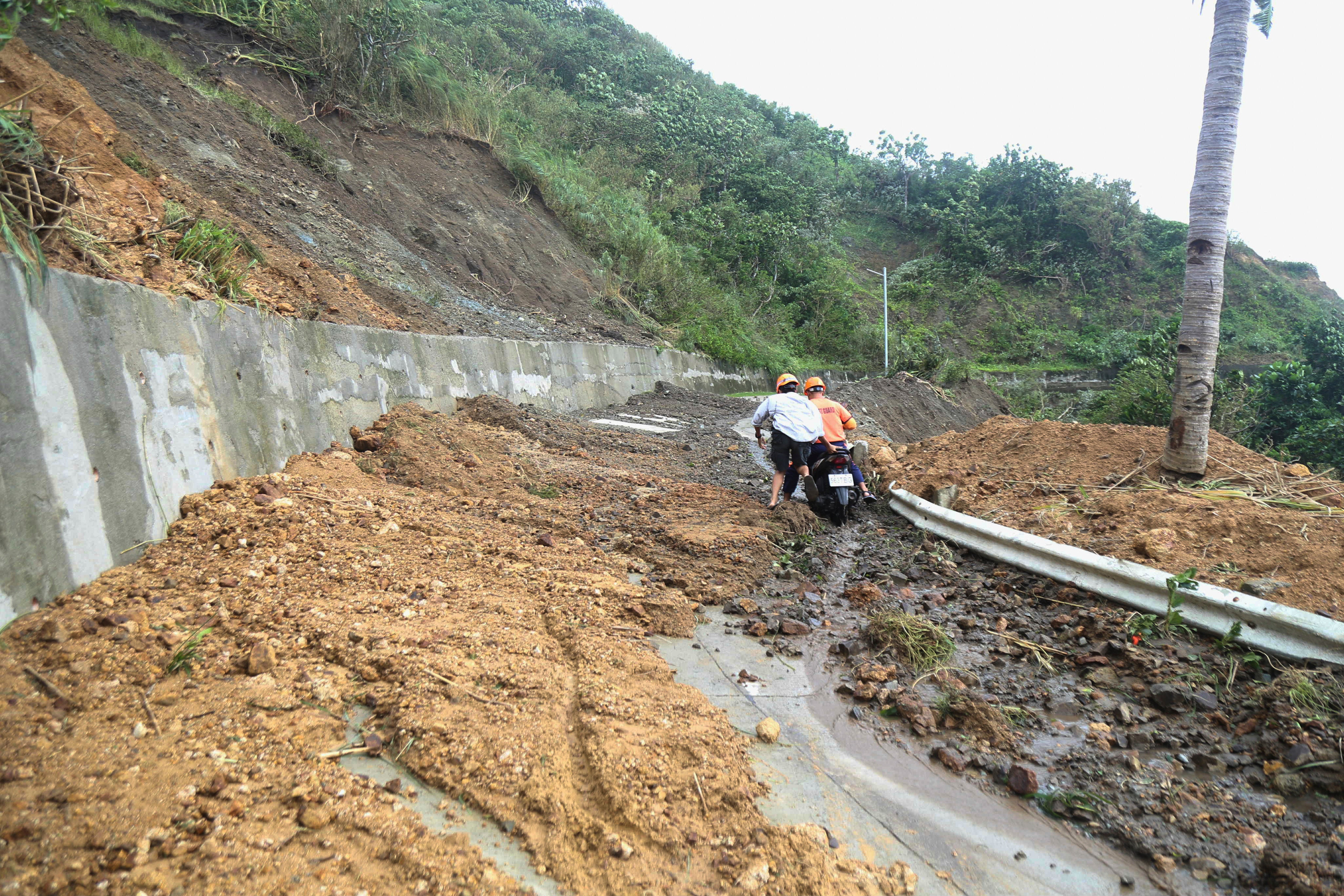 Two men negotiate a landslide due to Typhoon Ragasa in Uyugan, Batanes province, northern Philippines