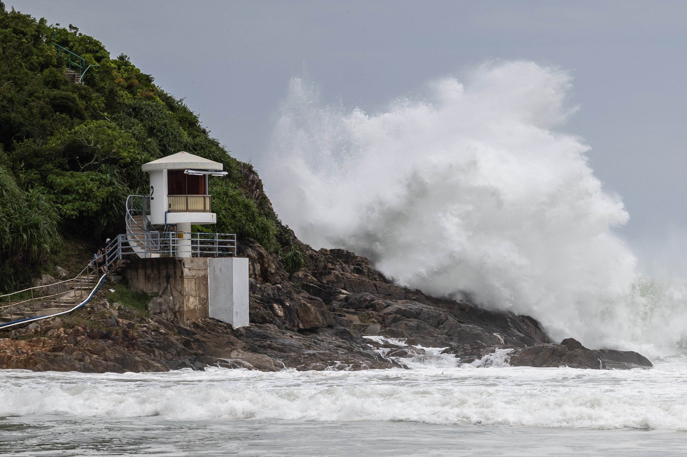 A large wave breaks behind a lifeguard tower at a beach as Ragasa moves towards Hong Kong